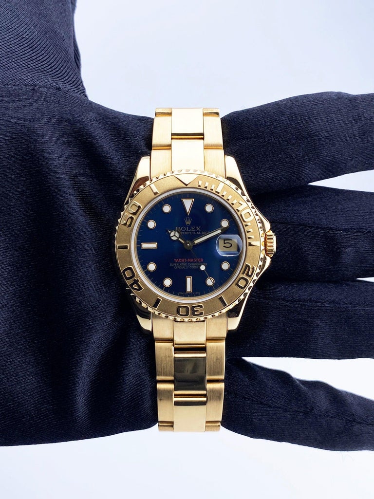 Rolex Yacht-Master 68628 Watch. 35mm 18K yellow gold case. 18K yellow gold bi-directional rotating bezel. Blue dial with luminous gold hands and luminous dot hour markers. Minute markers on the outer dial. Date display at the 3 o'clock position. 18K