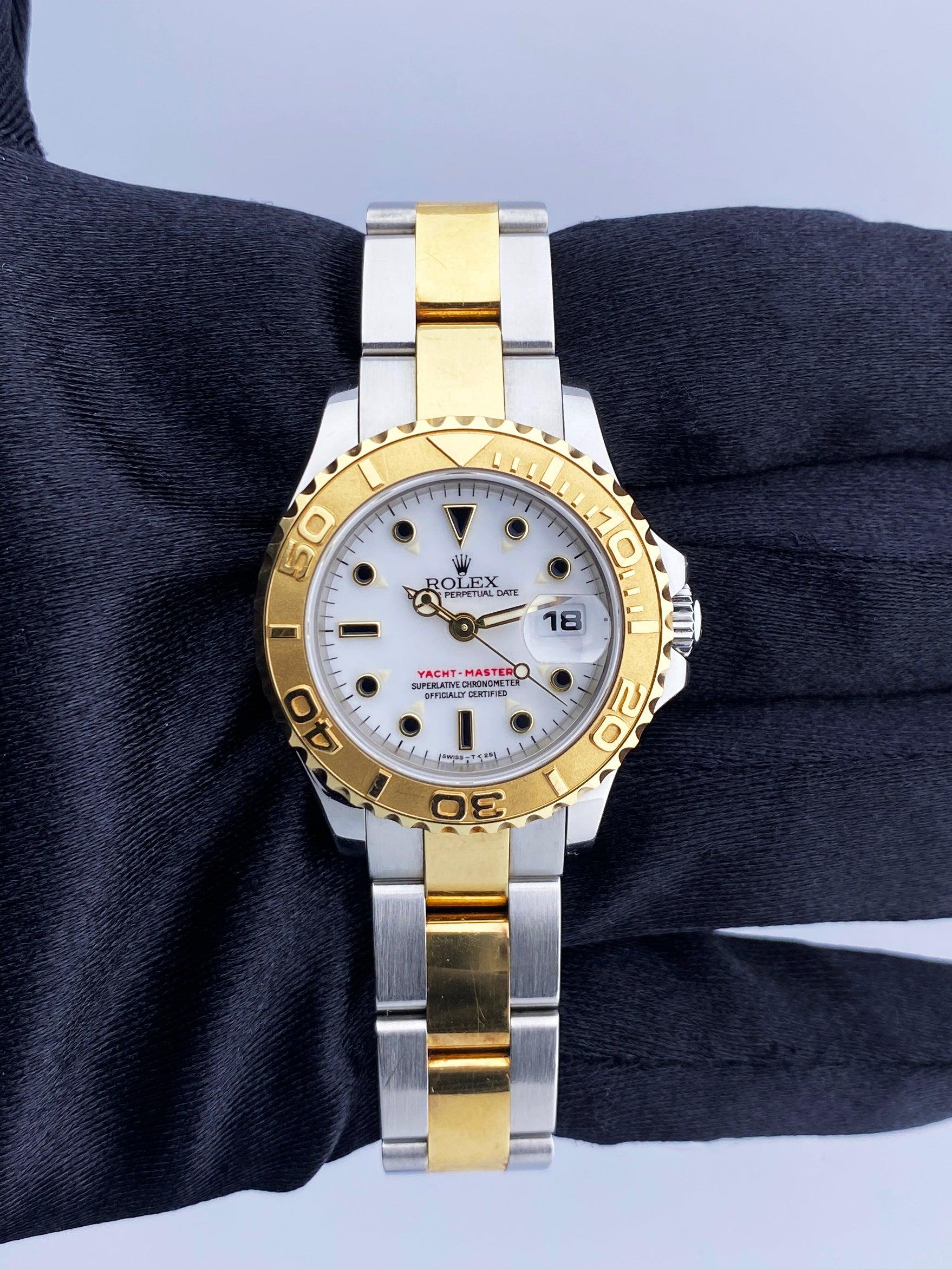 Rolex Yacht-Master 69623 Ladies Watch. 29mm stainless steel case. 18K yellow gold bi-directional rotating bezel. White dial with luminous gold hands and dot hour markers. Minute markers on the outer dial. Date display at the 3 o'clock position. 18K