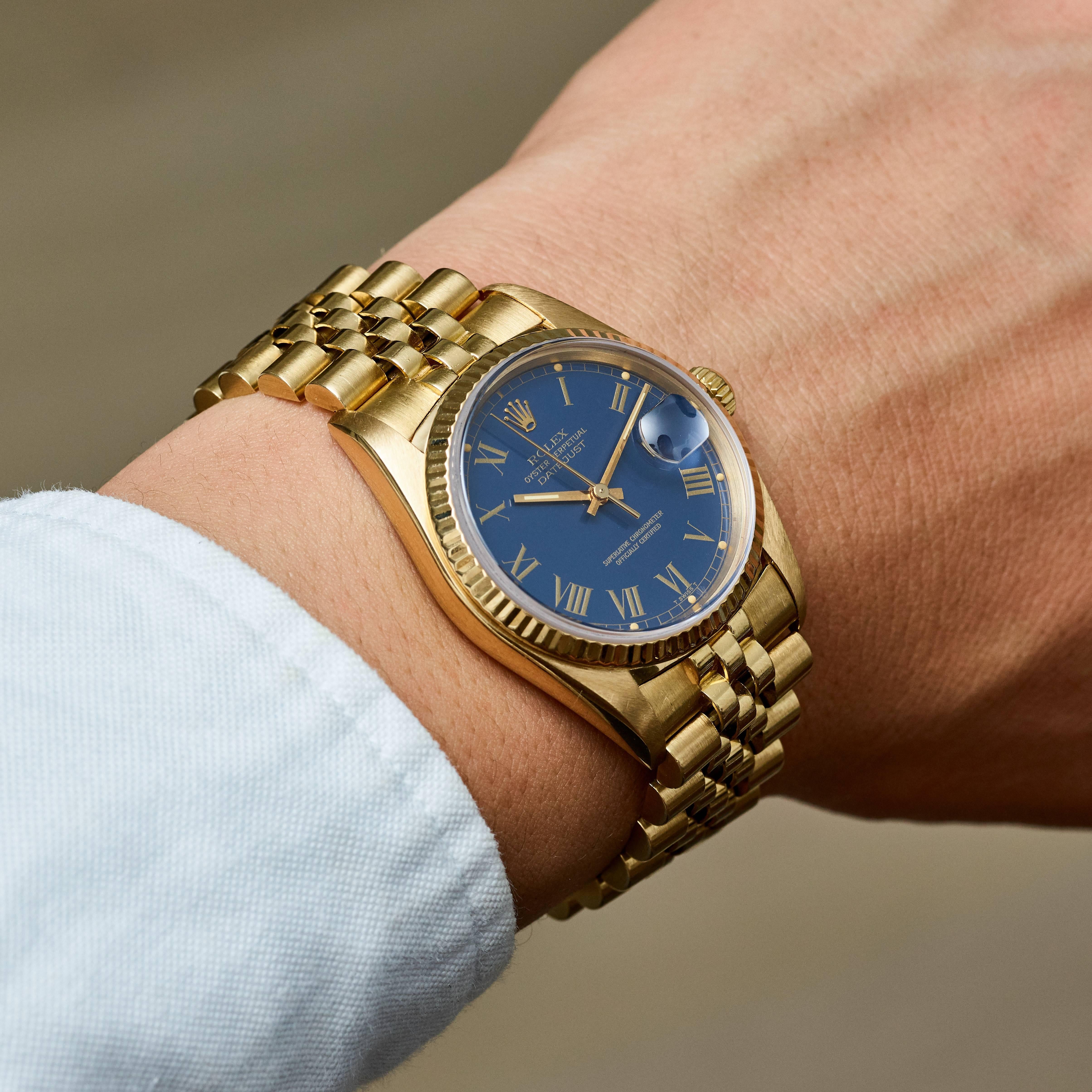 Rolex 18K Yellow Gold Oyster Perpetual Datejust Wristwatch
Factory Blue 'Buckley' Dial with  Roman Numeral Markers with Creamy Pumpkin Colored Lume Plots
18K Yellow Gold Fluted Bezel
36mm in size 
Rolex Calibre Base 3035 Automatic Quick-Set