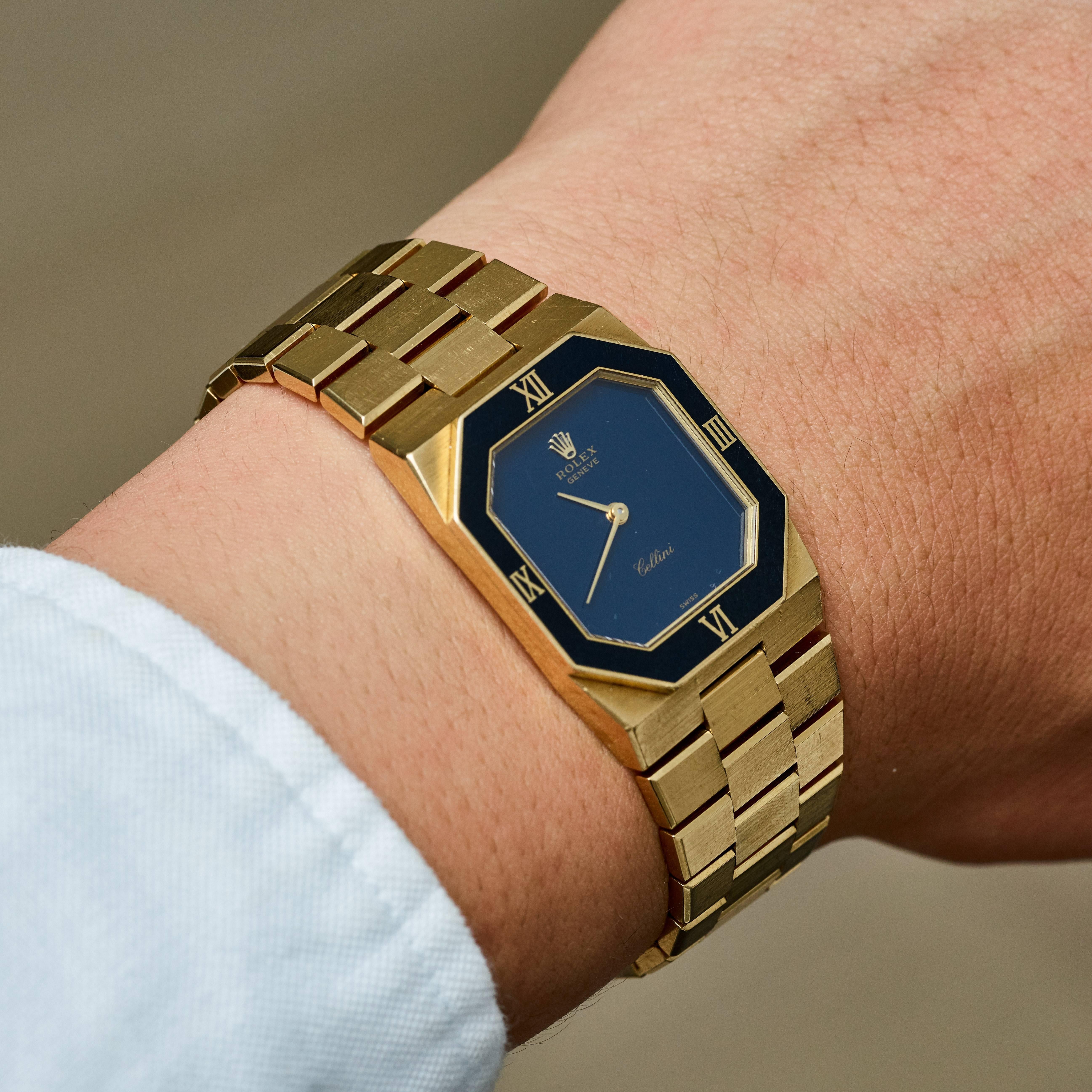 Rolex Cellini 18K Yellow Gold Manual Wind Wristwatch
Factory Blue Stone Dial with Applied Rolex Crown
Solid 18K Yellow Gold Case and Bracelet
Dark Blue Geometrical Bezel ( Bezel shows some signs of wear and marks) with Roman Numeral Markers 
24mm x