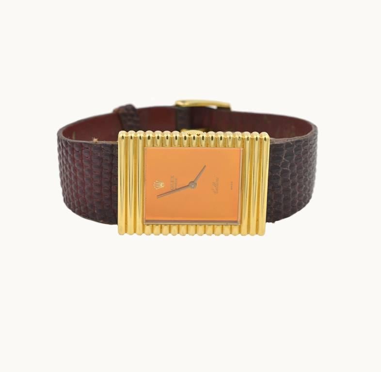 Rolex Cellini wristwatch in 18 karat yellow gold with a mirrored orange color dial, reference 4012.  This watch features a 19 jewel manual winder 1600 caliber movement, glass crystal, Rolex plaque buckle on a brown leather lizard strap. Circa 1973.