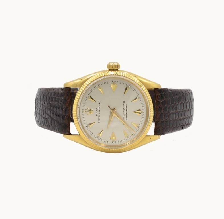 A Rolex Oyster Perpetual Chronometer wristwatch in 18 karat yellow gold, reference 6567. This beautiful Rolex features a 18 karat yellow gold oyster case, a 18 karat yellow gold fluted bezel, plastic crystal, silvered dial with gold triangular