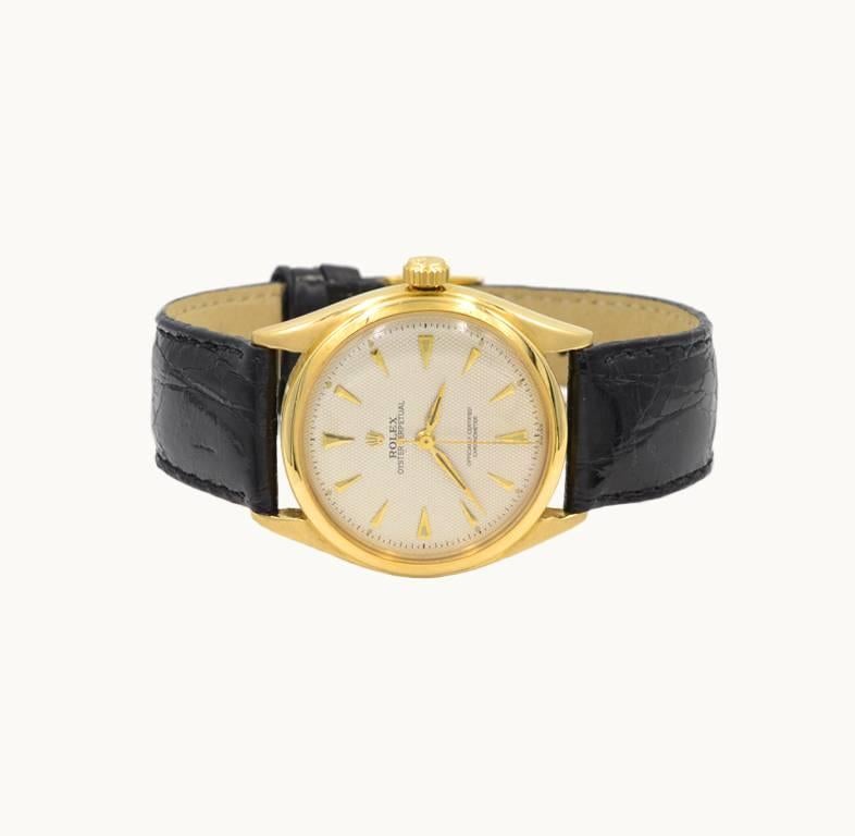 A Rolex Oyster Perpetual wristwatch in 18 karat yellow gold, reference 6084. This beautiful Rolex features a 18 karat yellow gold oyster case, a 18 karat yellow gold smooth bezel, plastic crystal, textured waffle dial with gold triangular markers, a