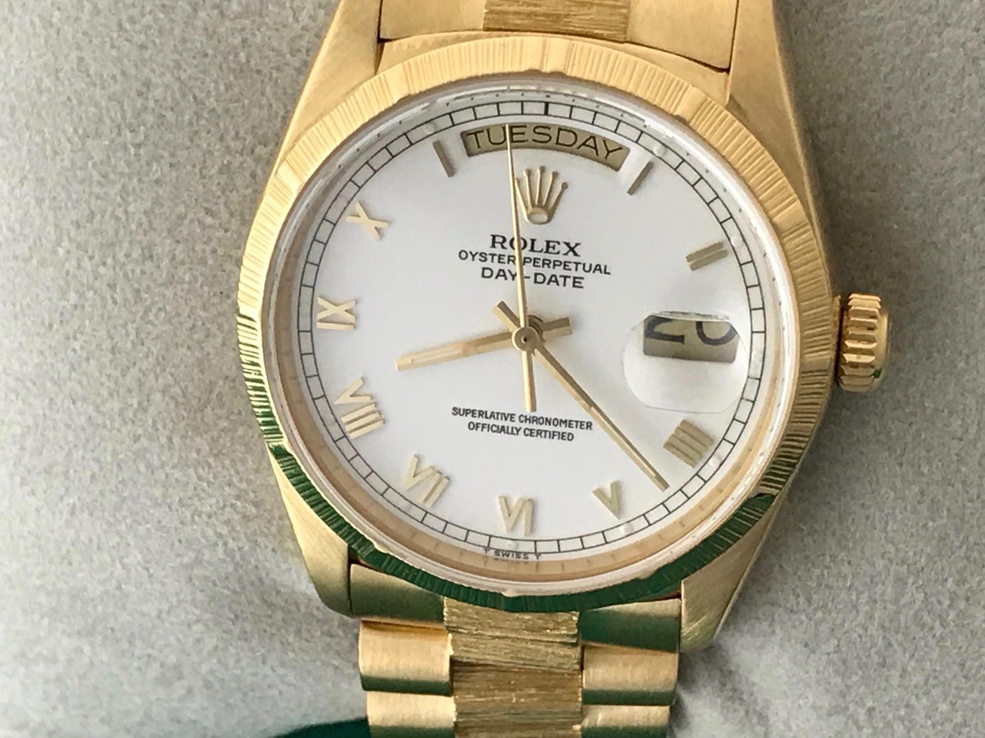 Rolex President Day-Date Model 18078 Pre Owned Mens  Automatic wrist watch. White Dial with yellow gold Roman numerals. 18k Yellow Gold case with barked bezel (35mm). 18k Yellow Gold hidden clasp President bracelet with barked center links. Rolex
