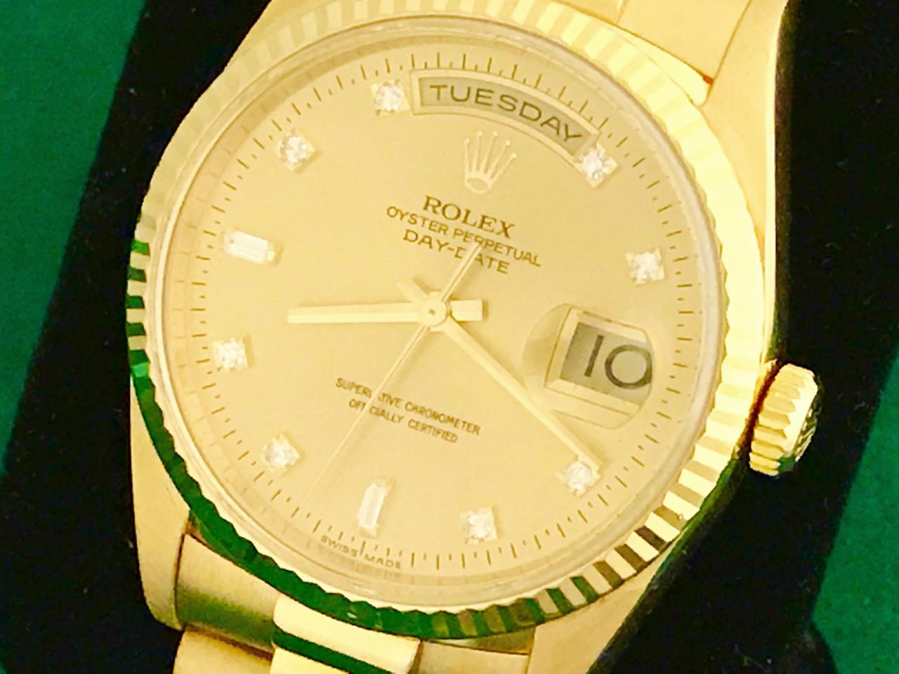 Rolex President Day-Date Model 18238 Pre Owned Mens  Automatic wrist watch. Rolex Champagne Dial with Diamond hour markers (8 rounds & 2 baguettes). 18k Yellow Gold case with fluted bezel (35mm). 18k Yellow Gold hidden clasp President bracelet.