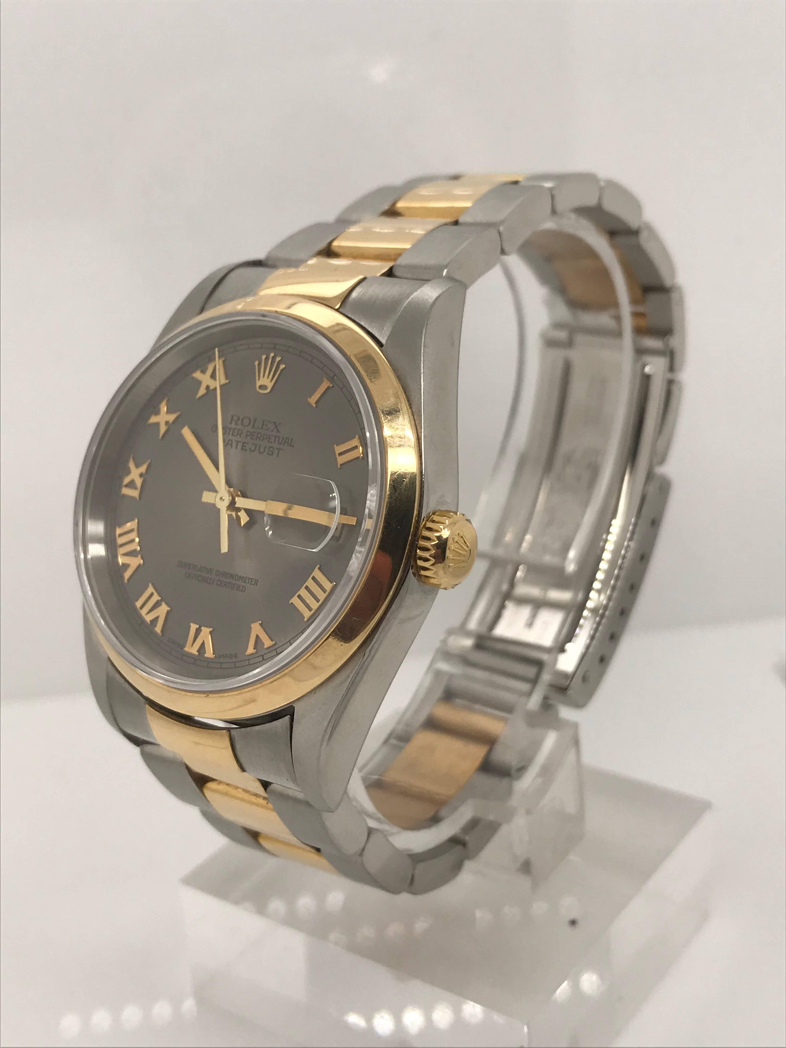 This two-tone, 18kt yellow gold and Stainless Steel Rolex Datejust features a unique slate gray dial with golden Roman Numeral markers. This watch is on an Oyster link 18kt and Stainless steel link style bracelet. Circa 2003. This timepiece has been