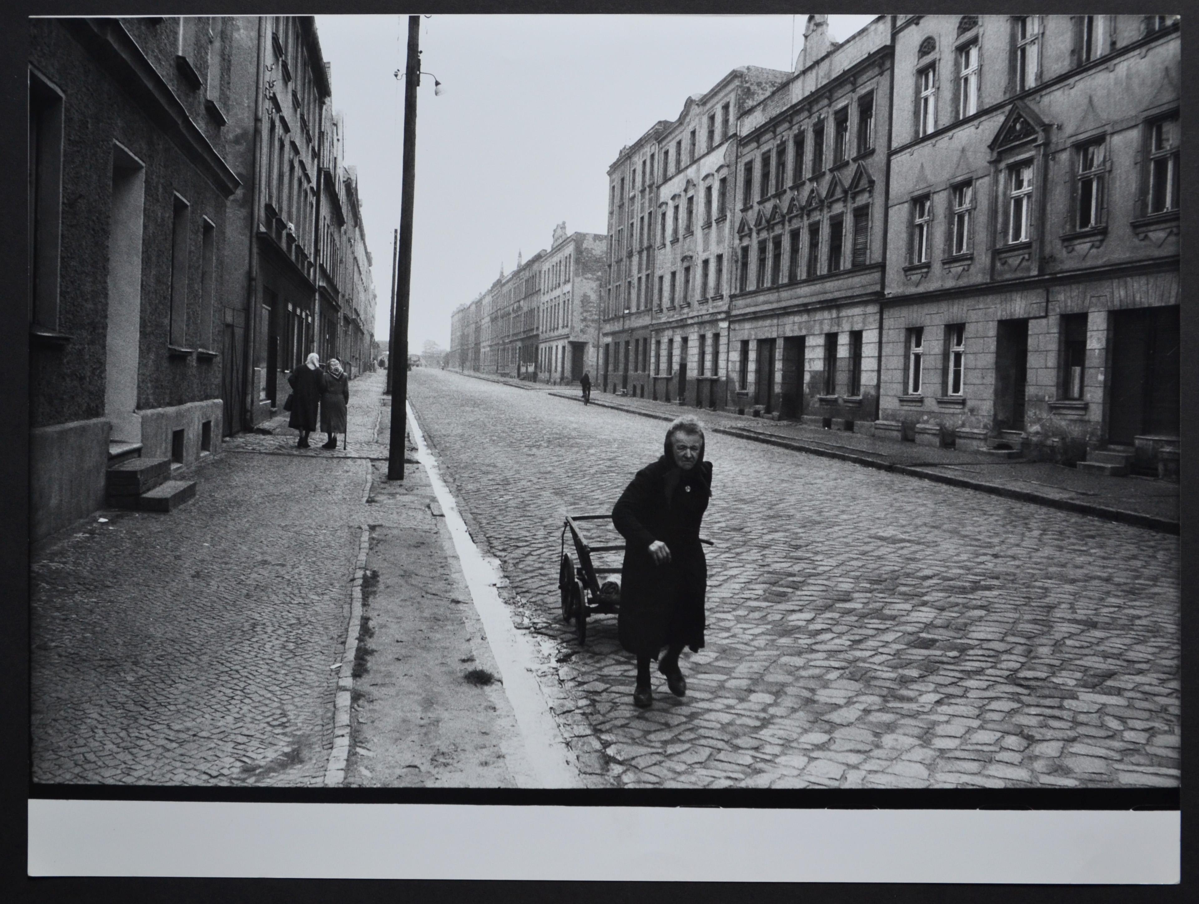 Rolf Gillhausen Black and White Photograph – Eine ältere Frau, die mit ihrem Handwagen auf der Straße geht, 1940er bis 1950er Jahre.