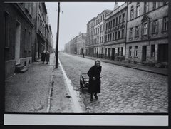 Eine ältere Frau, die mit ihrem Handwagen auf der Straße geht, 1940er bis 1950er Jahre.