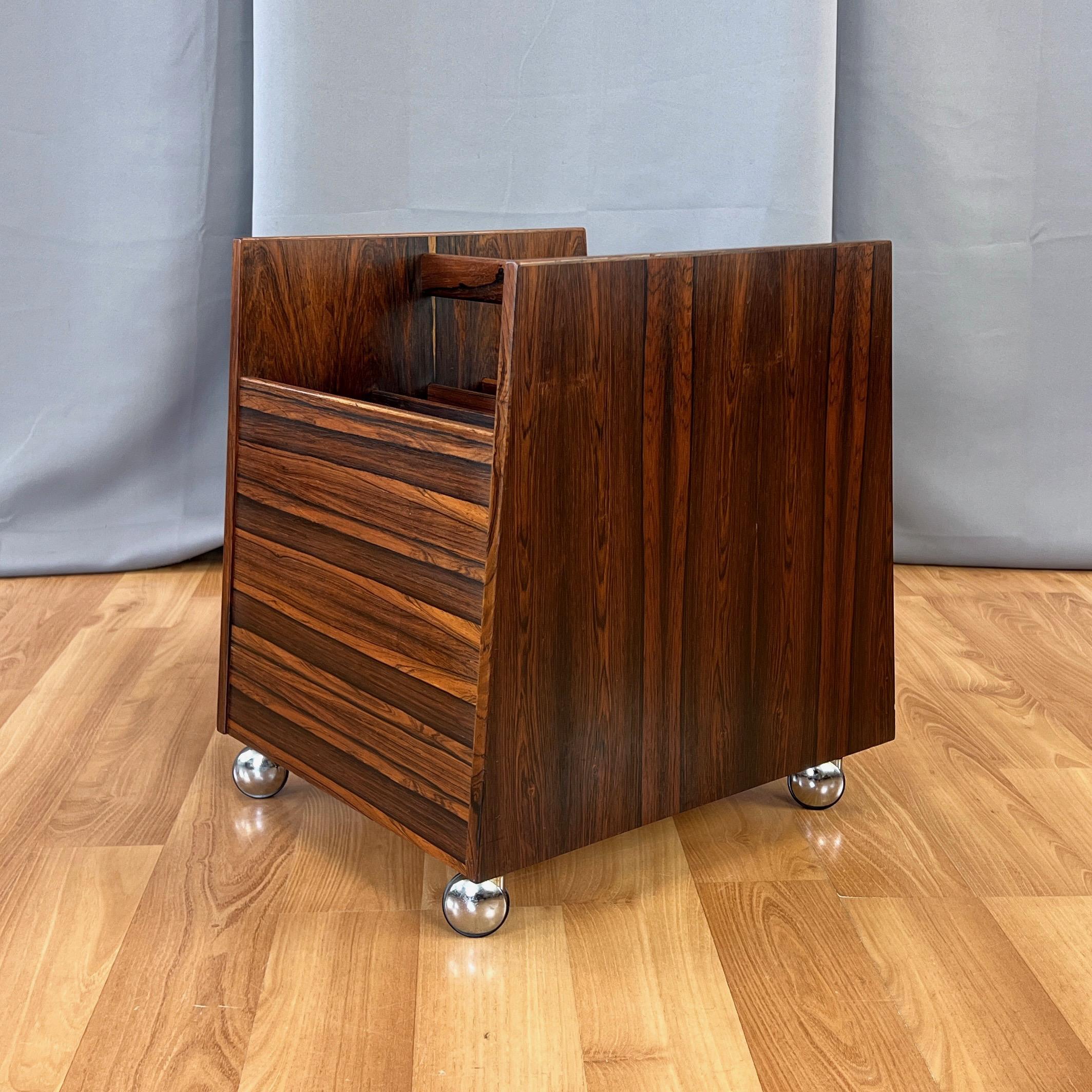 A strikingly good-looking 1960s Norwegian rosewood magazine and LP rack or caddy on caster wheels designed by Rolf Helsand and produced for Bruksbo by Mellemstrands Trevareindustri. 

Clean lines with a timeless Scandinavian modern design that