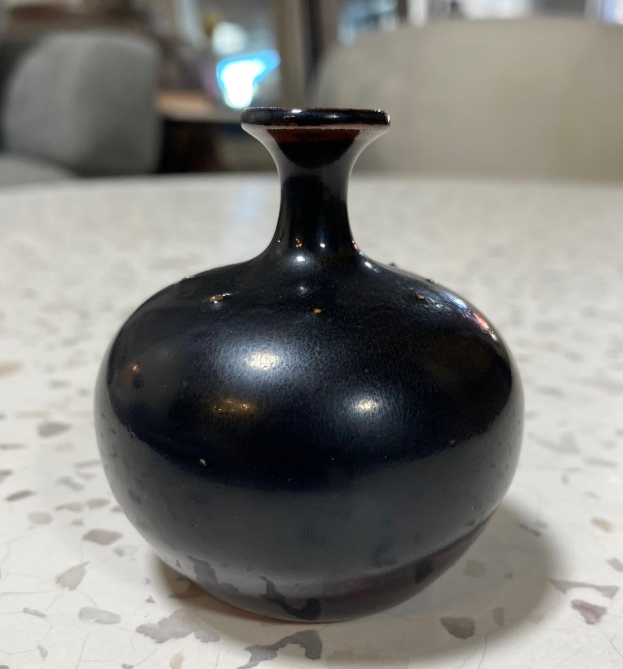 A beautiful and darkly glazed miniature vase by Swedish master ceramicist/designer Rolf Palm for Mölle, Sweden. This gem features a Classic shape with tiny spines and a rich glaze that radiates and changes colors (blacks, browns, with a tinge of