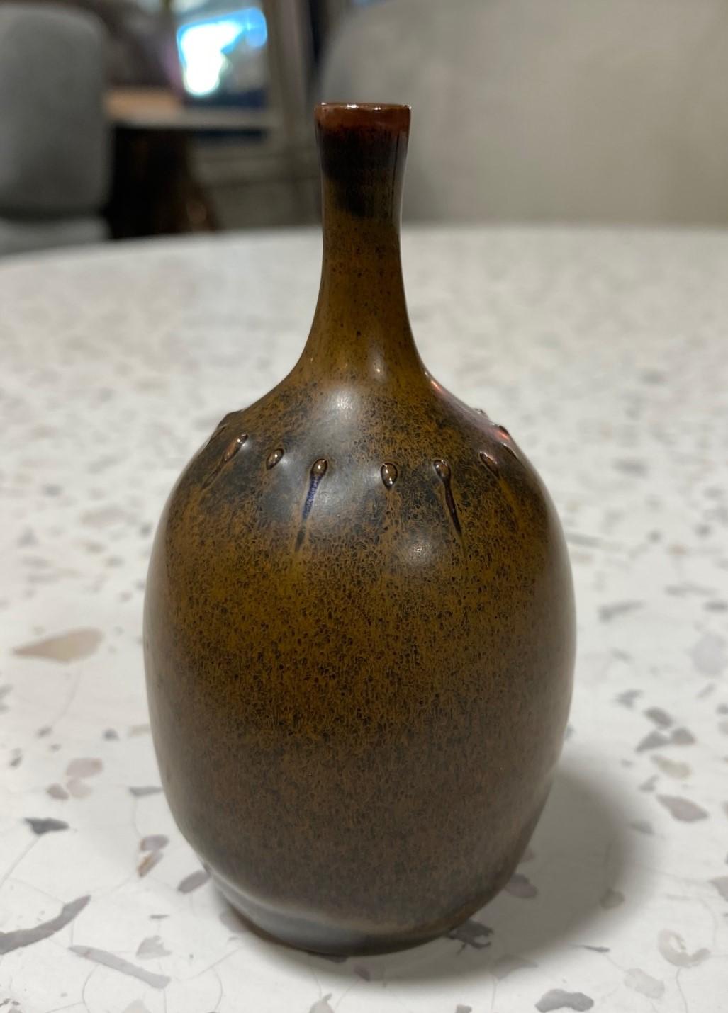 A beautiful and darkly glazed miniature vase by Swedish master ceramicist/designer Rolf Palm for Mölle, Sweden. This gem features a Classic shape with tiny spines and a rich glaze that radiates and changes colors (browns, greens, with a tinge of