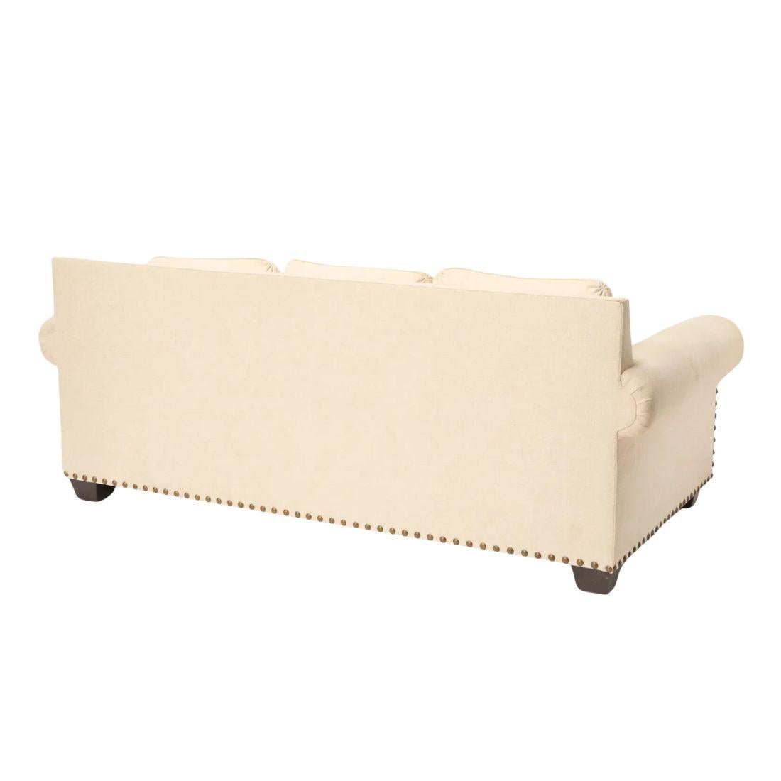This sophisticated roll-arm cream sofa exudes timeless elegance with its classic design and refined details. The large nailhead trim runs along the back, arms and base, adding a touch of character and distinction. The sofa features a comfortable