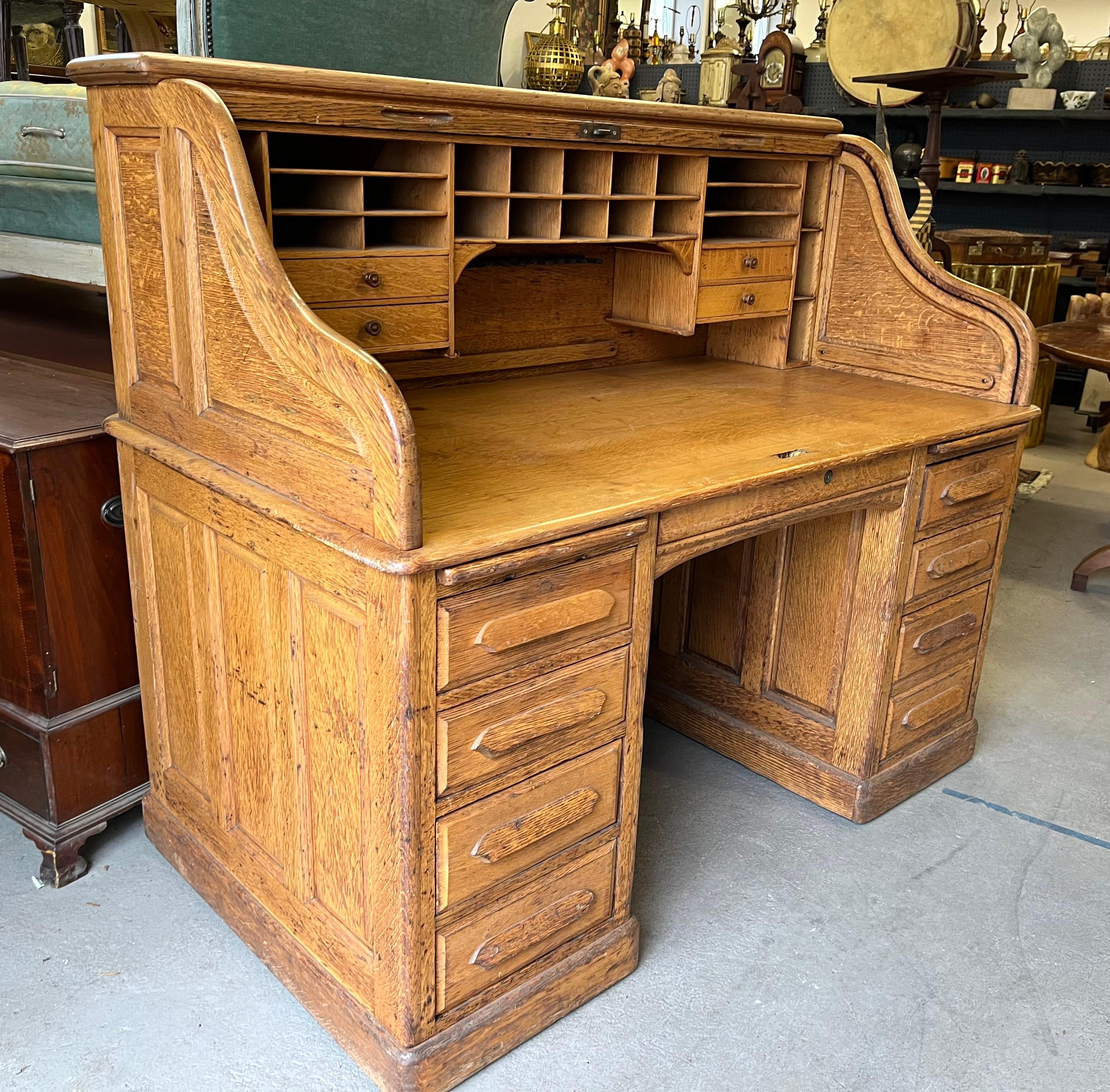 A nice “S-scroll” roll top desk in golden oak by Derby Co. of Boston, circa 1920, with double banks of drawers, interior compartments and paneled on all sides. Nice old finish in great working order. Tan or roll too works smoothly. Very clean. 
