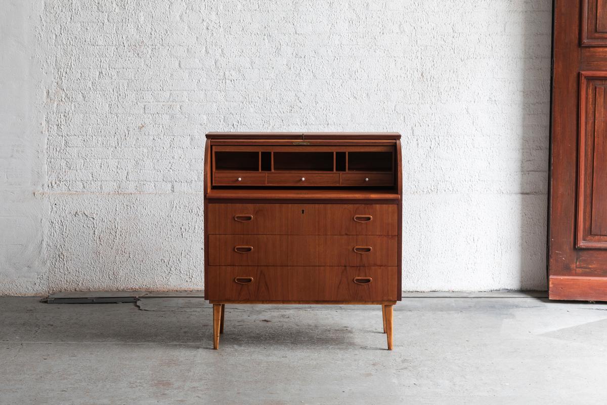 Roll top secretary designed by Egon Ostergaard for MSI, Sweden during the 1960’s. Solid teak and teak veneer. The upper rolltop opens on three small drawers and neat compartments above a slide-out writing desk surface. The three lower drawers have