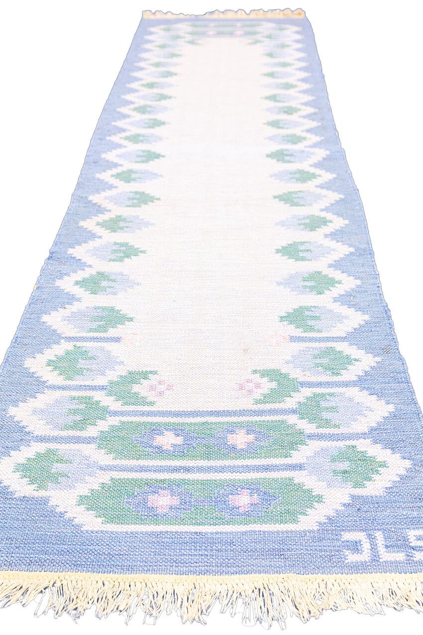 Entrez dans un monde de sophistication vintage avec notre tapis suédois Rollakan dans un style captivant, fabriqué pendant la période de 1950 à 1970. Ce tapis est une capsule temporelle d'une élégance intemporelle, alliant le charme d'une époque