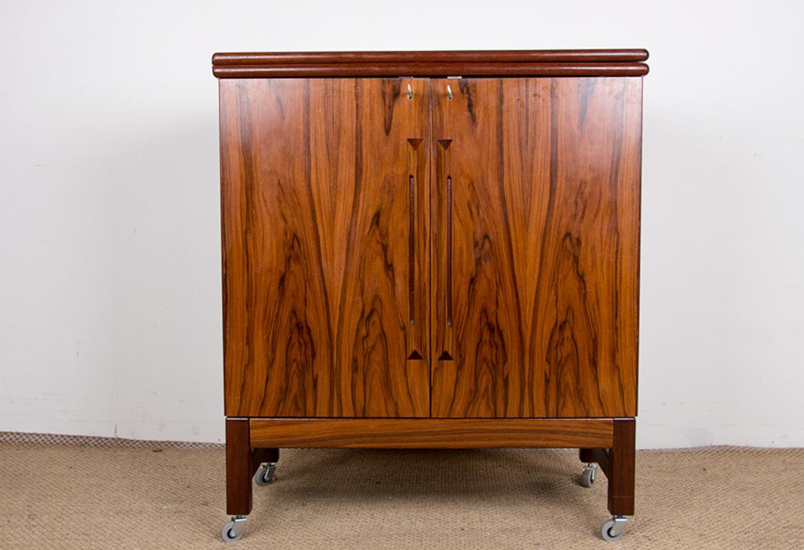 Superbe bar scandinave sur roues. 
Le plateau recouvert de linoléum noir coulisse et se déplie pour couvrir toute la largeur du meuble ouvert ou fermé et en faire un bar 