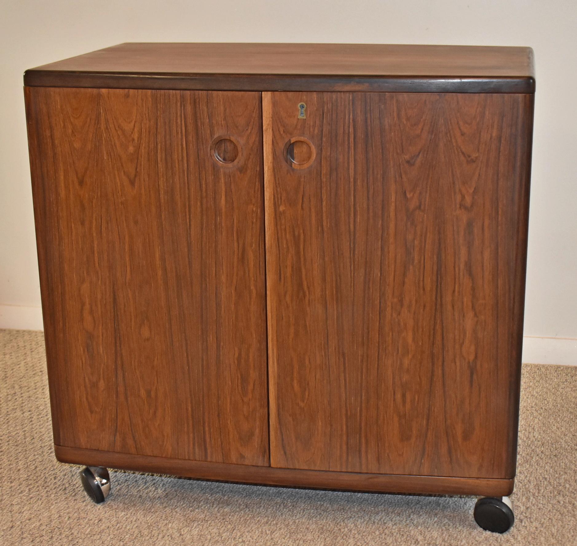 Rolling Bar Cabinet in Rosewood from CFC Silkeborg. Danish Mid-Century Rosewood drinks cabinet designed by Illum Wikkelso and produced by Silkeborg Mobelfabrik (CFC) in the 1960's. The cabinet features shelving to the backs of the twin doors, bottle