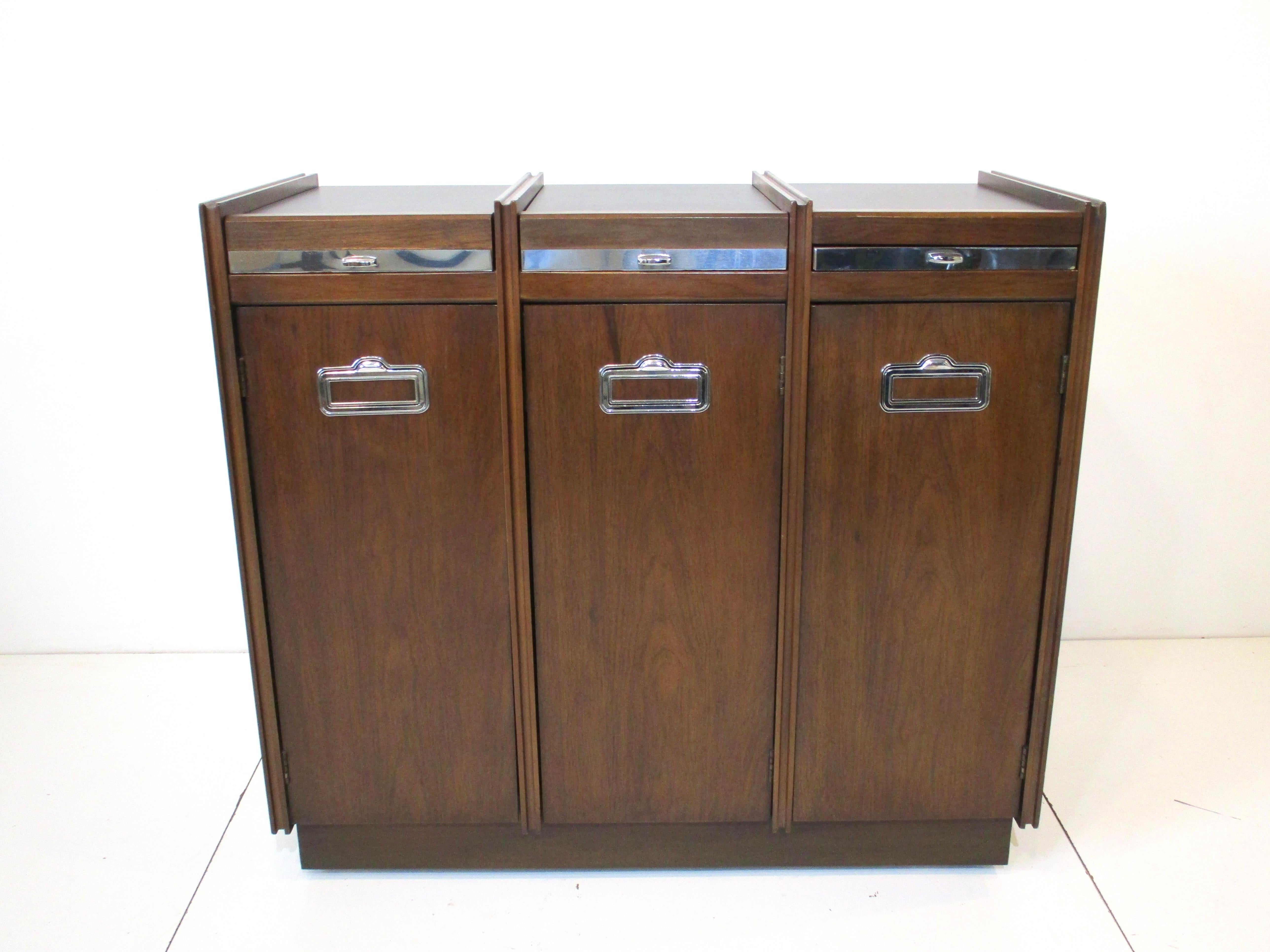 A very versatile dark mahogany rolling bar serving cabinet with laminate top having three functions. The first and second are flip up lids that reveal serving wear storage the second has a storage compartment, the third has a pull out mixing