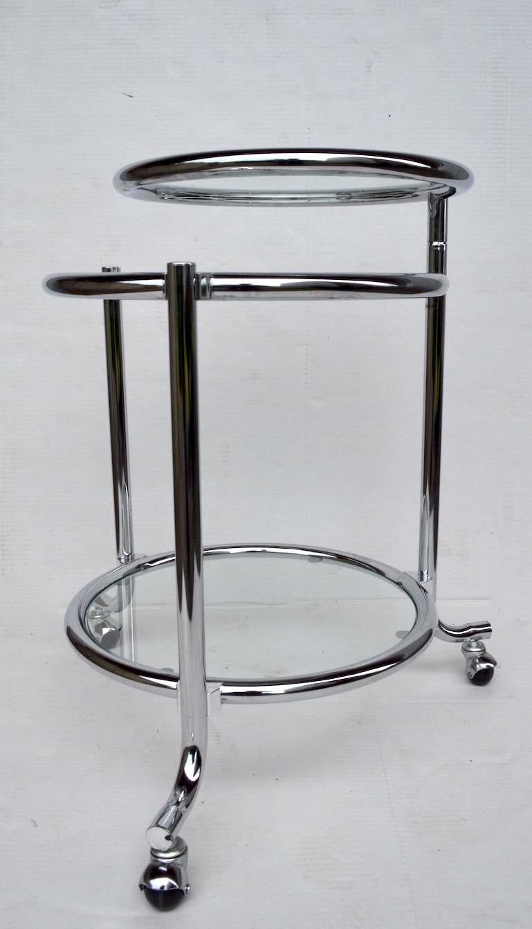 Stylish tubular chrome serving / bar cart with three chrome ring and glass tray surfaces. The top disk tray surface is adjustable, pivoting out from the centre post, as shown. Well made, and in very fine original condition, clean and ready to use.