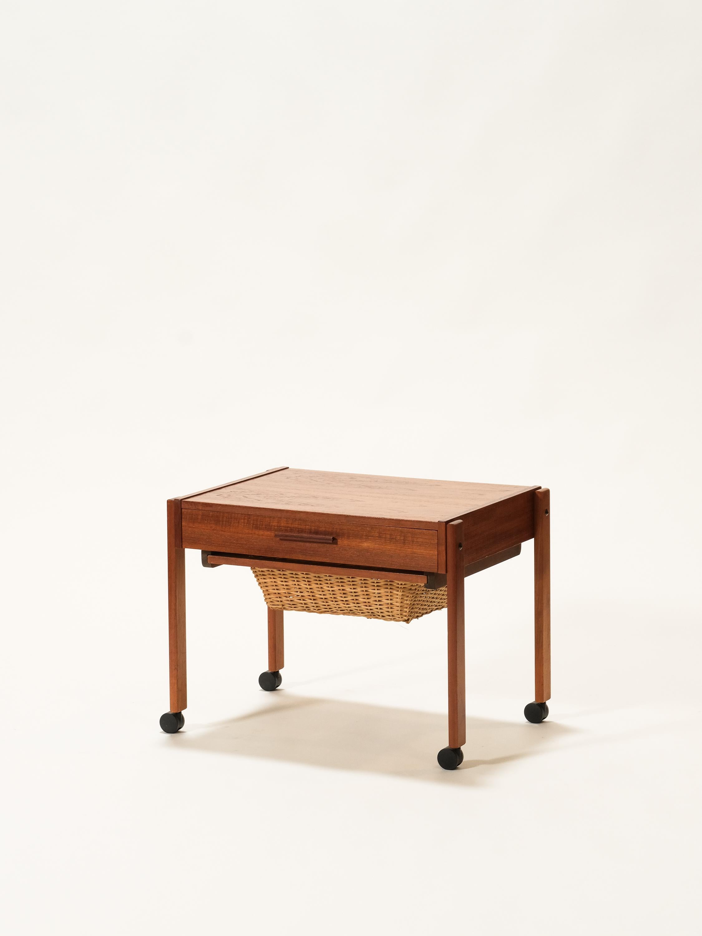 This teak mid-century trolley is designed for textile crafts such as knitting or sewing but can also be used as a bar cart or side table. Rattan basket slides out from underneath the table top, drawer has very useful dividers. In original condition