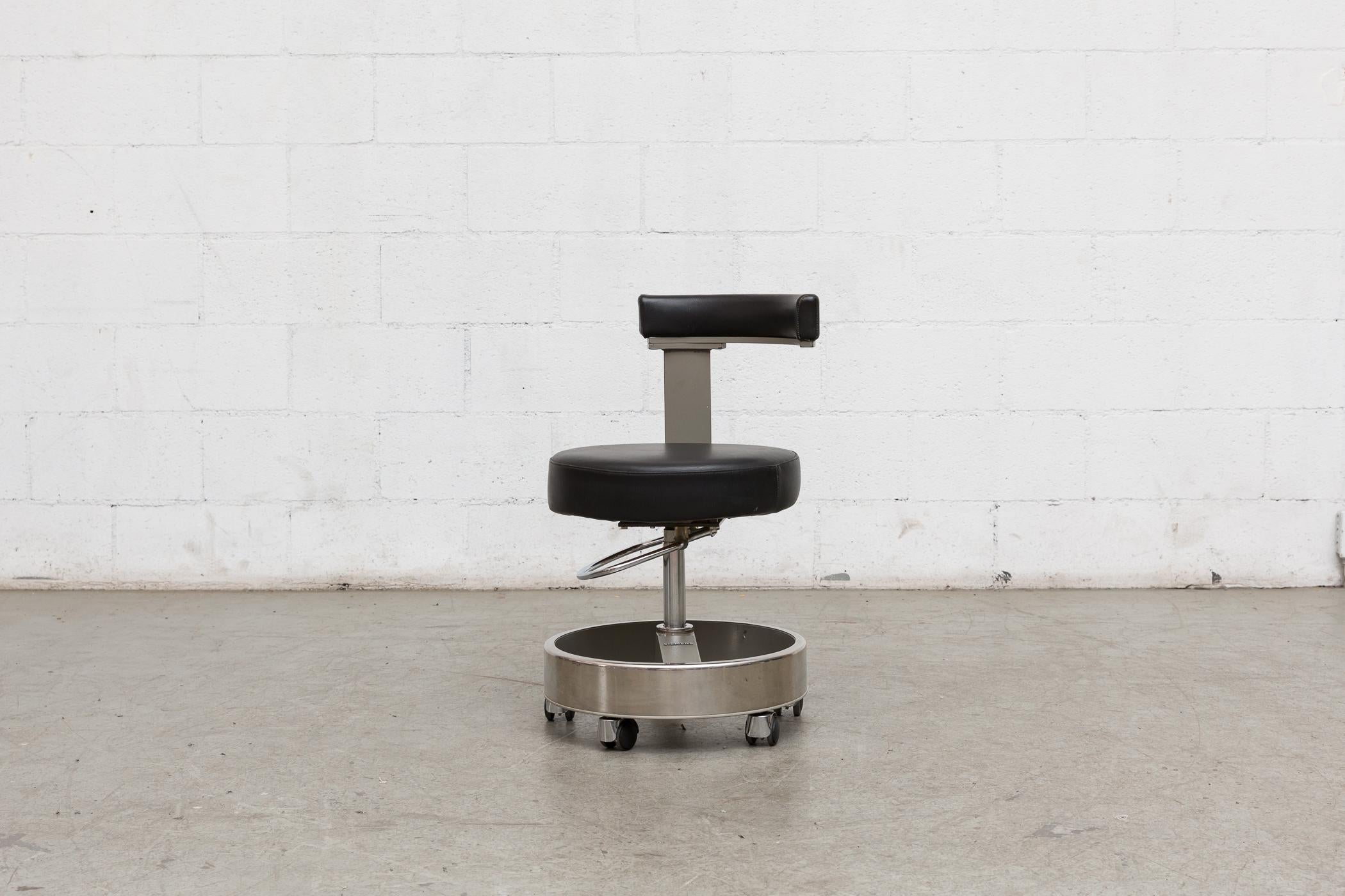 Rolling German dentist chair with asymmetric seat back. Manufactured by siemens in Germany. Black leather upholstery and chrome frame with adjustable height. Manufacturer detail on foot rest.