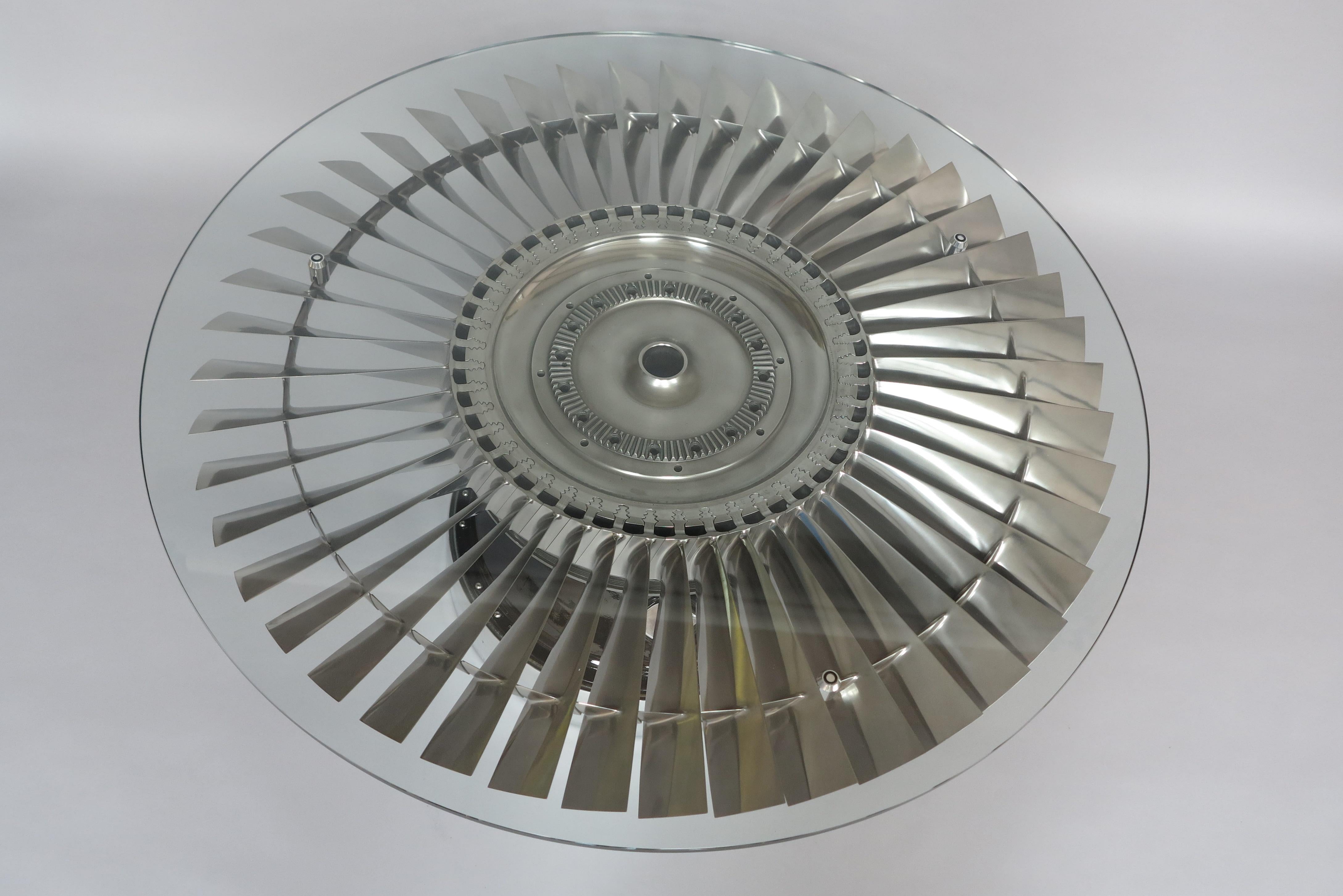 A simply stunning coffee table with 45 highly polished titanium blades, forming a complete LP2 (Low pressure 2) jet turbine from a Harrier Jump Jet. The base to which the turbine is fixed to is from within the actual jet engine and can be polished
