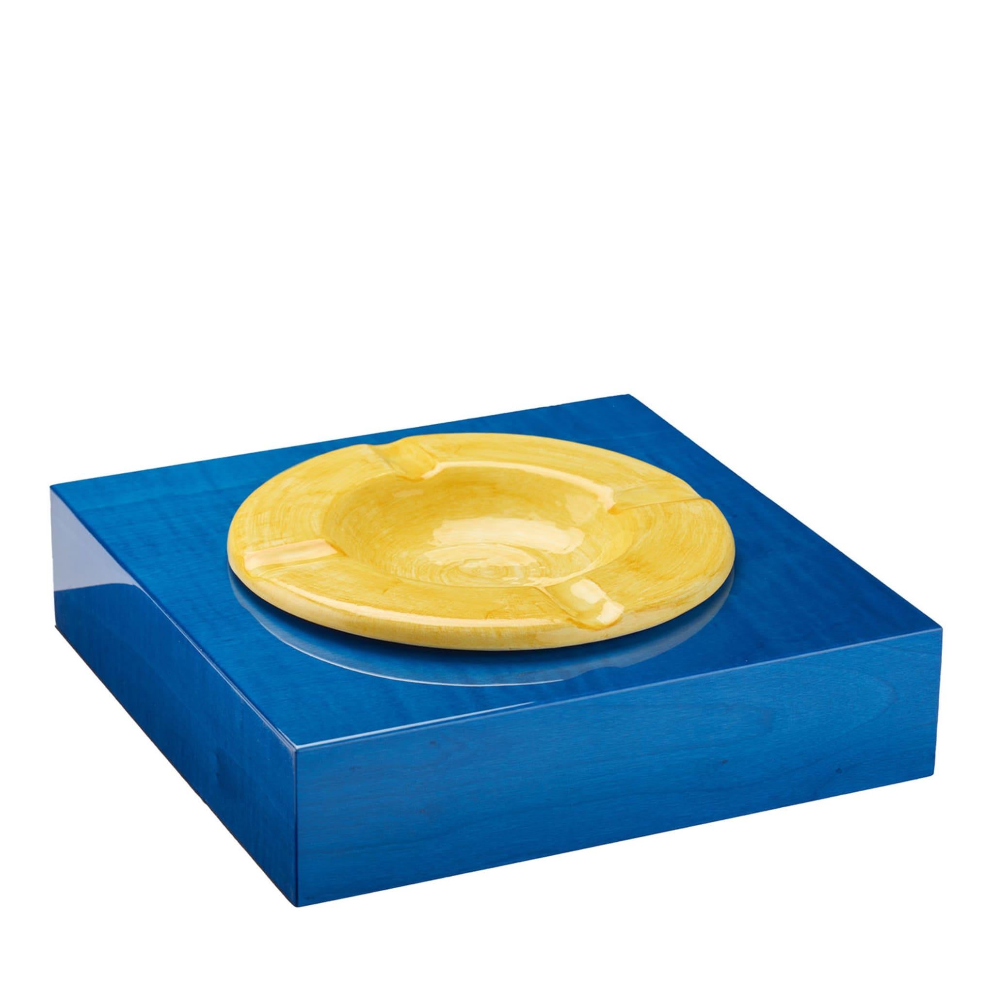 Showcasing splendid veinings through the polished blue and yellow paint decorating its square and clean shape, this ashtray turns an everyday object into a refined piece of interior design. Handmade of wood and ceramic, it is also finished and