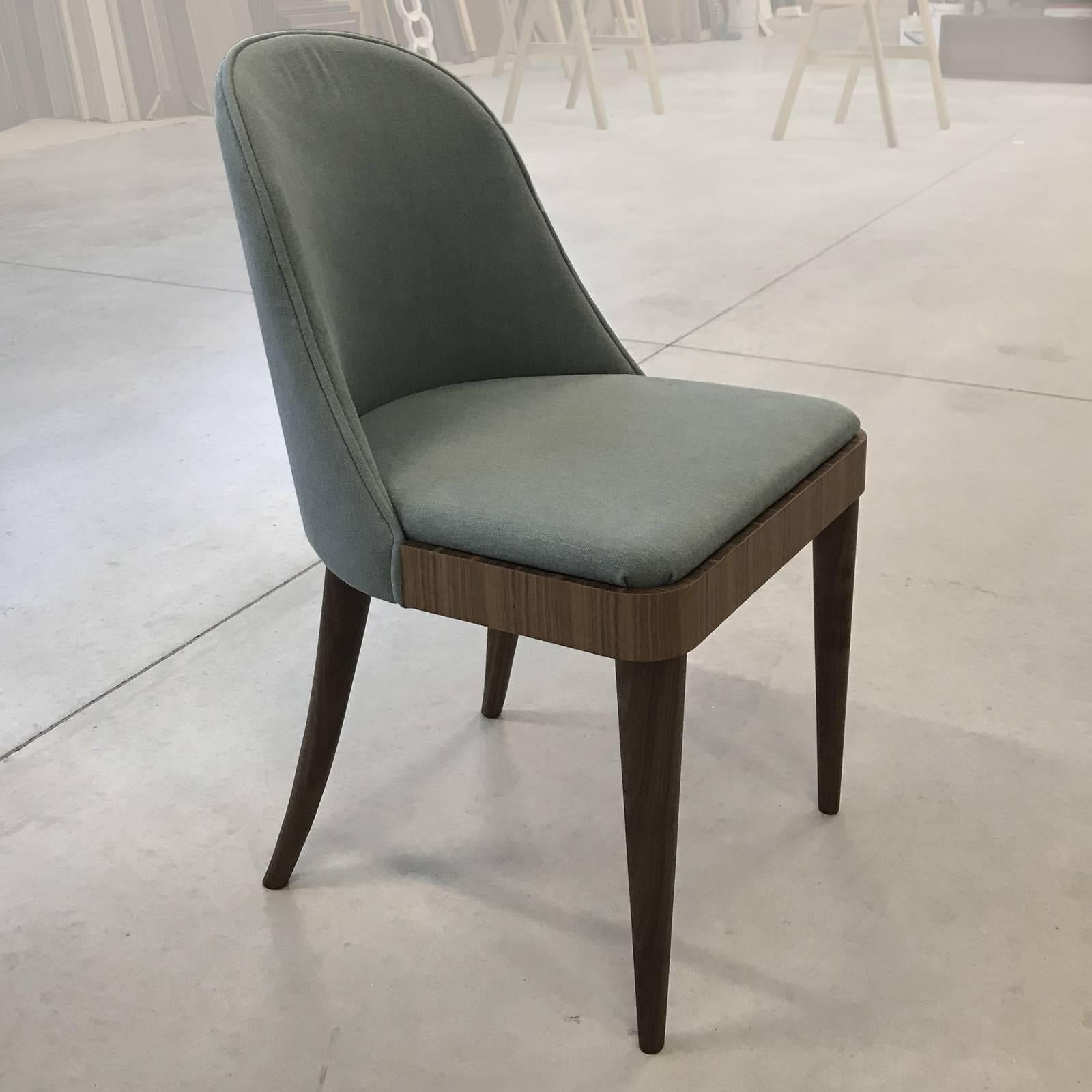 This elegant chair with its mid-century allure, is entirely made in solid Canaletto walnut wood. The finish of the wood can be natural or grey and the cushions can be upholstered in leather or fabric. Contract and commercial certifications available