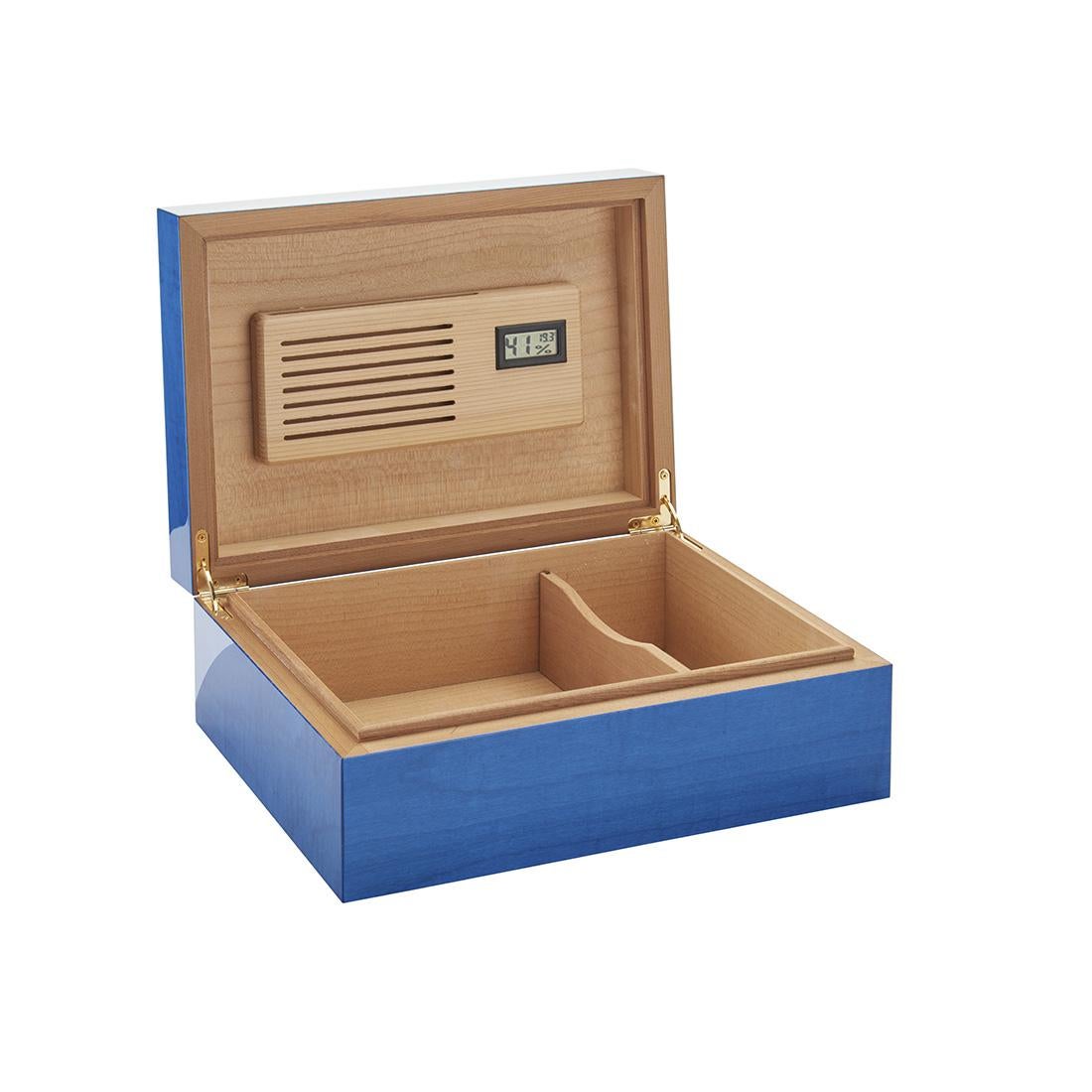 Painted in a delicate blue shade enhancing its stunning natural grains, polished and brushed by hand with polyester for a luminous mirrored finish, this cigar box is a sublime display of artisanal craftsmanship. Handmade of cedar wood, enriched with