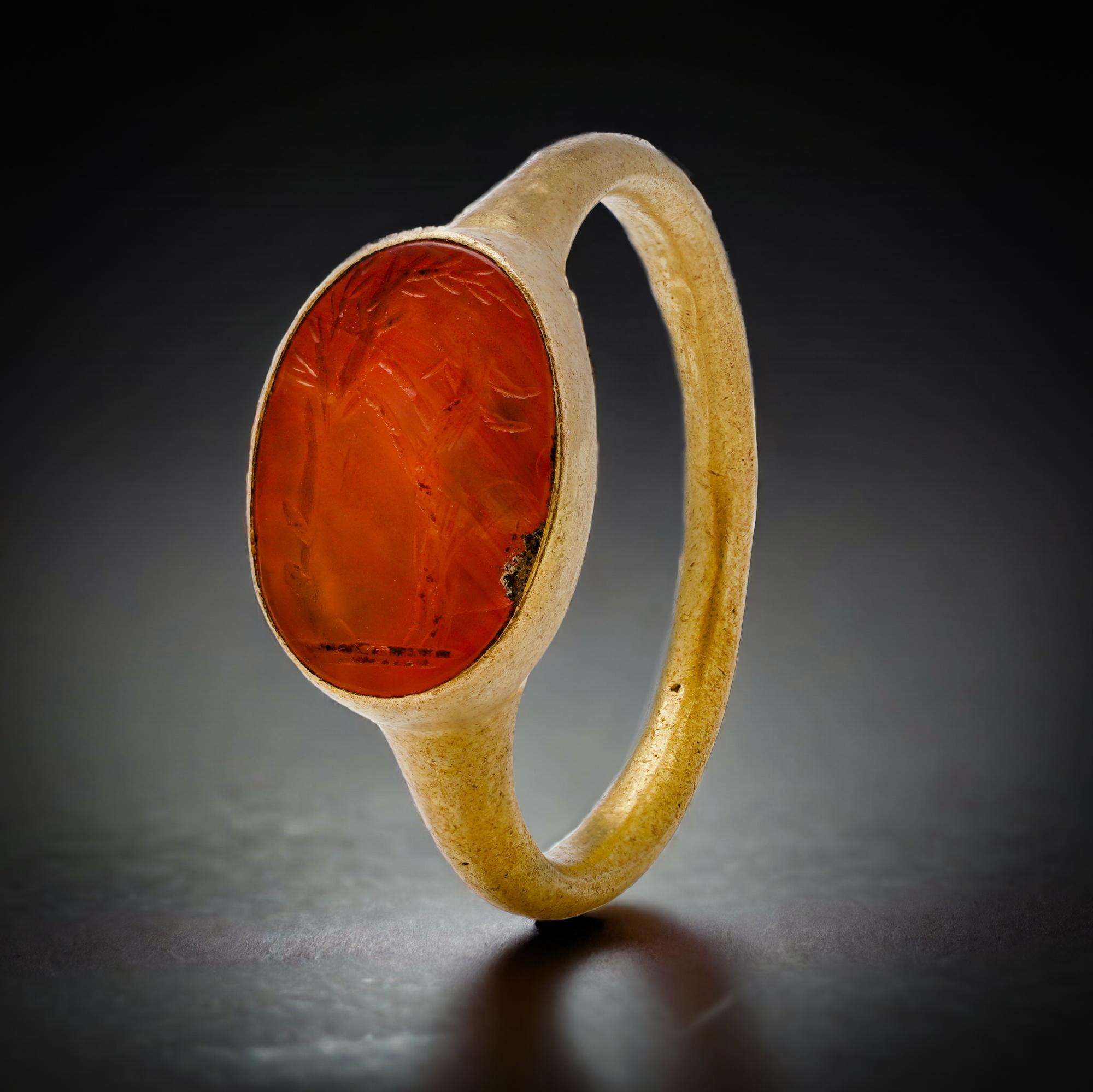 Roman 22kt. gold ring with goat carnelian intaglio.
Circa 100 - 300 AD. 

A lovely carnelian stone intaglio engraved with a goat rearing up a palm tree, set in a gold ring of a thin hoop, slightly expanding to support the bezel.

X - Ray tested