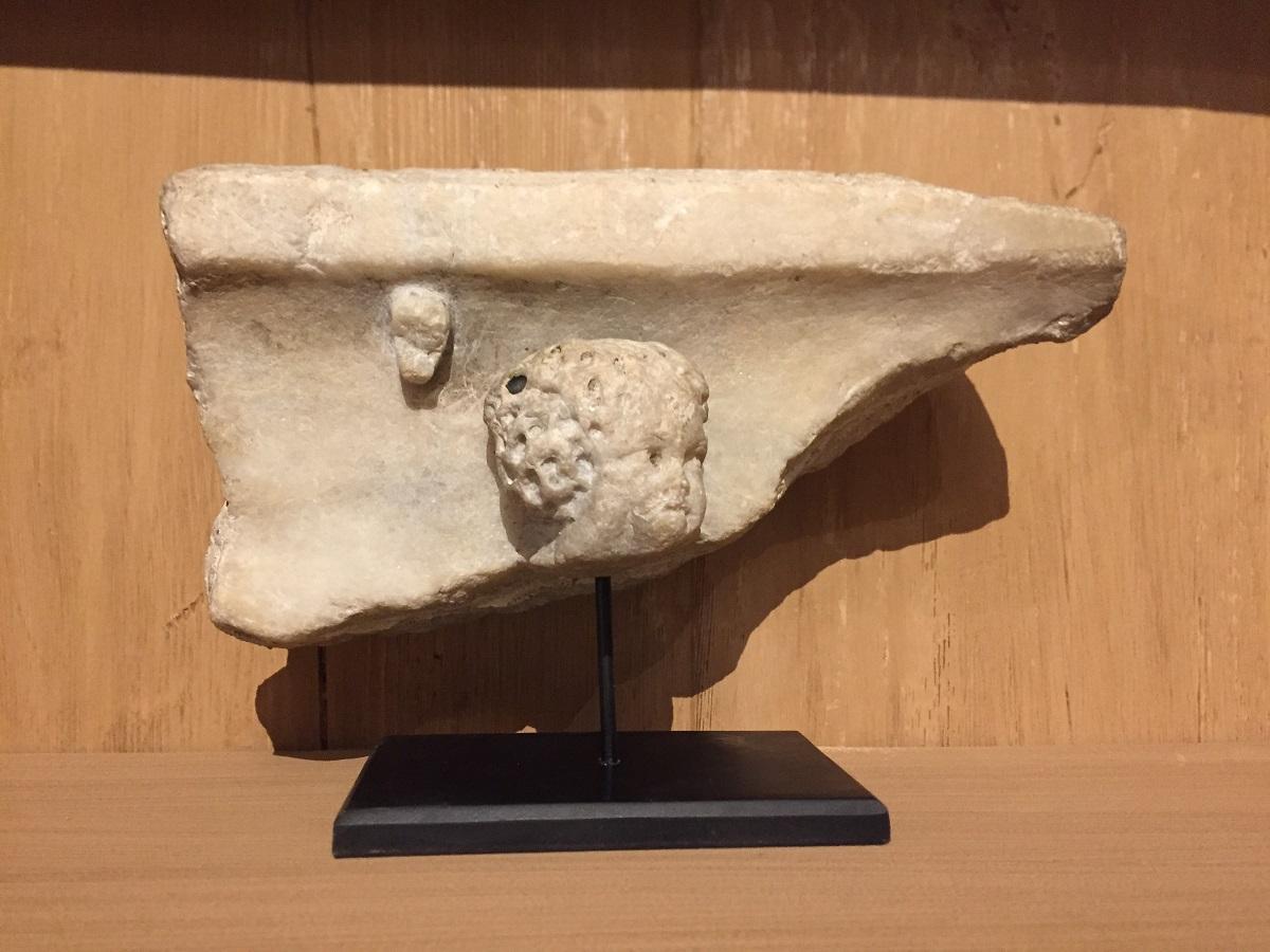 Roman architectural fragment of a frieze depicting the upper moulding above a putto face in white marble. Probably France 2-3th century AD.