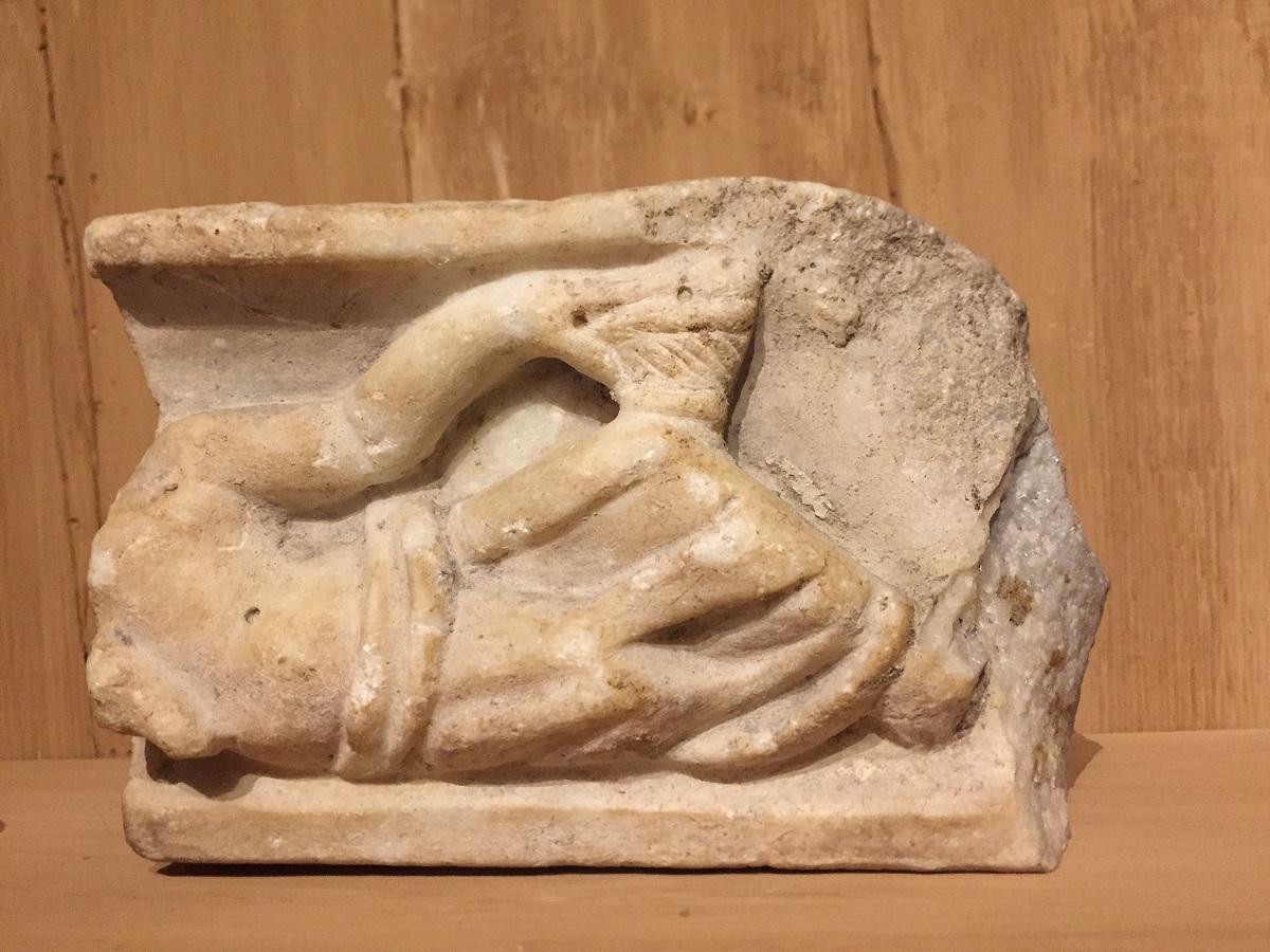 Roman architectural fragment in marble depicting a lying man, enclosed between mouldings, in toga holding a cup. This frieze fragment might have been part of a funerary stèle. It is finely sculpted with good details. Probably French circa 1-2st