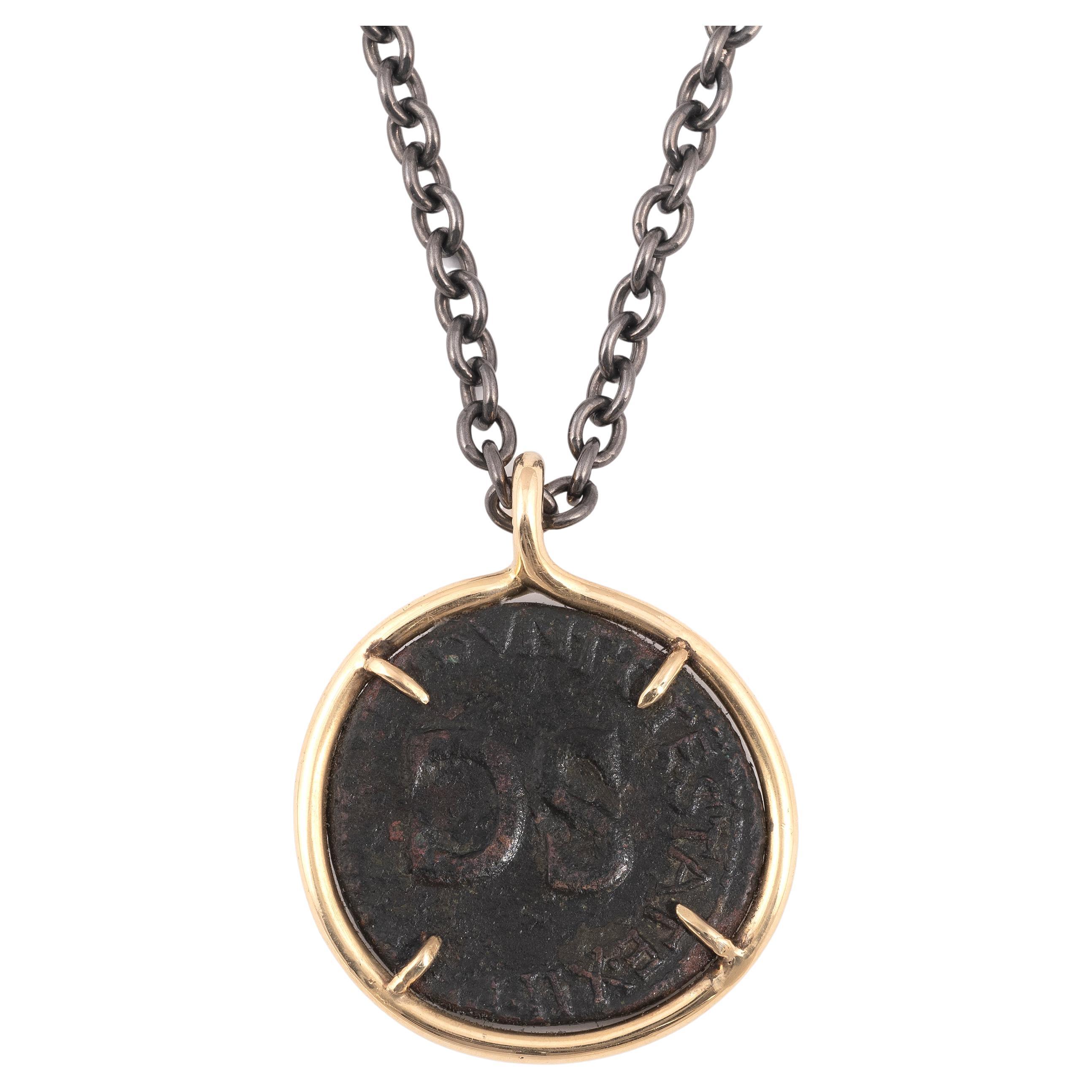 Pièce de monnaie romaine en bronze Tibère Pendentif en or 18kt 37 A.C. 
Sur une chaîne moderne en argent laqué noir avec fermoir en or 18 carats. (Diamètre de la pièce : environ 2,8cm - Longueur de la chaîne : 59cm).
TIBERIUS (19/08/14-16/03/37)