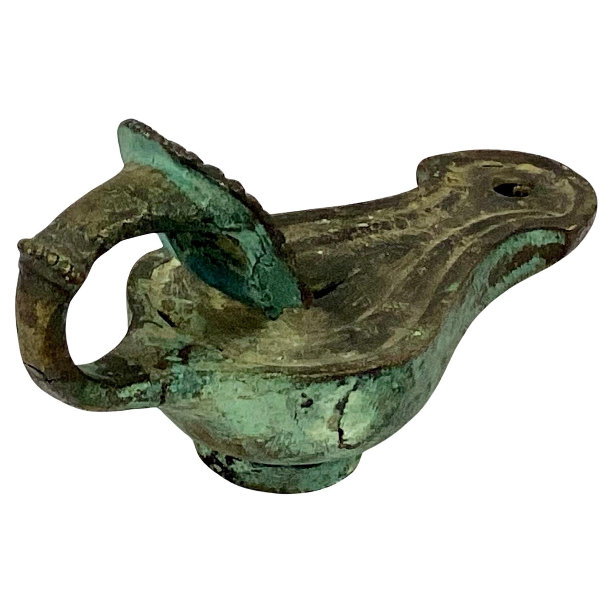 Rare lampe à huile en bronze coulé de la Grande Tour romaine, avec un corps en forme de poire menant à un bec courbé. La poignée a un masque de théâtre avec des traits expressifs et des cheveux bouclés serrés. Les lampes à huile étaient remplies