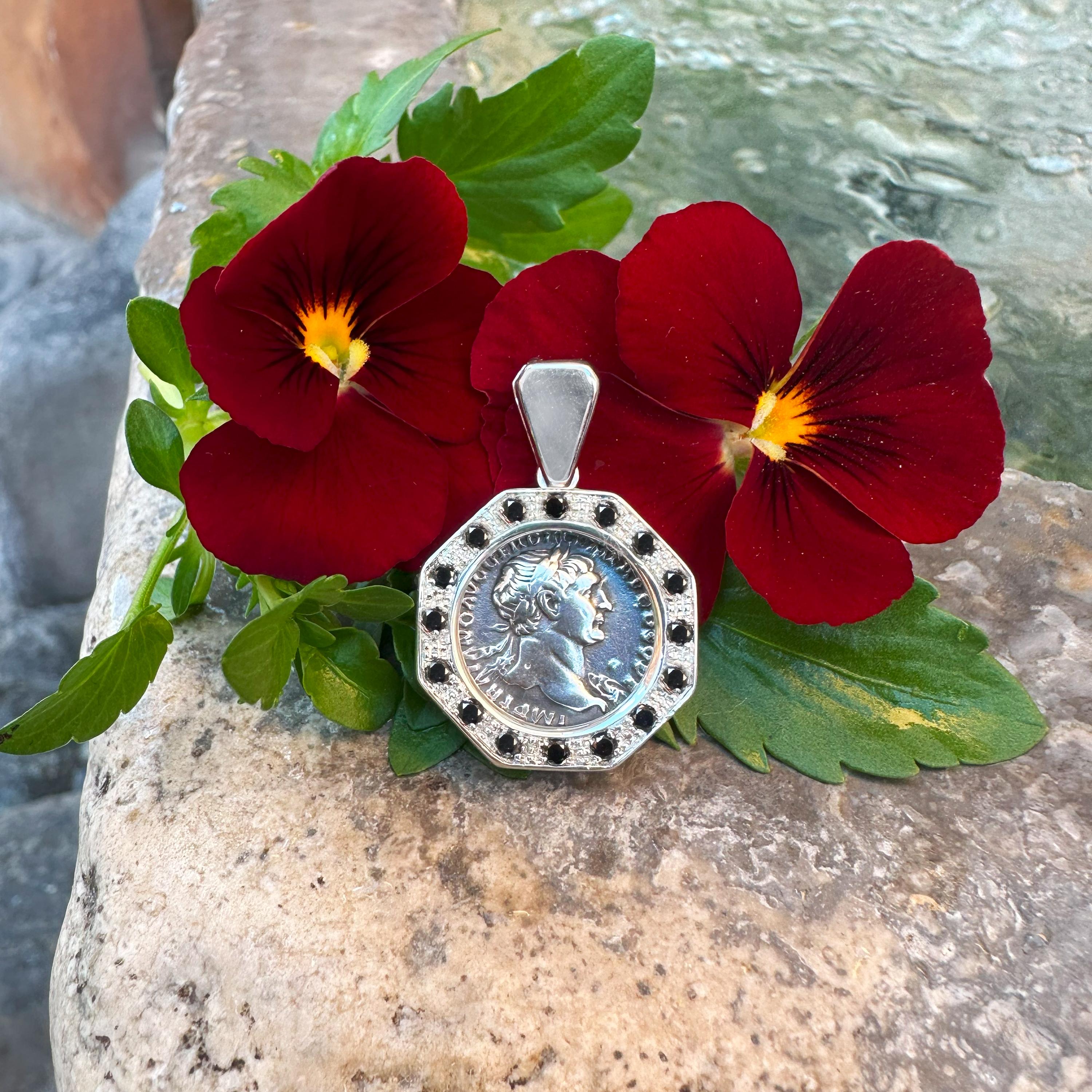 Cet exquis pendentif en argent met en valeur une véritable pièce de monnaie romaine en argent datant du IIe siècle après J.-C., représentant l'empereur Trajan au recto et le Genius Popoli Romani au verso. Le pendentif est rehaussé de 16 diamants