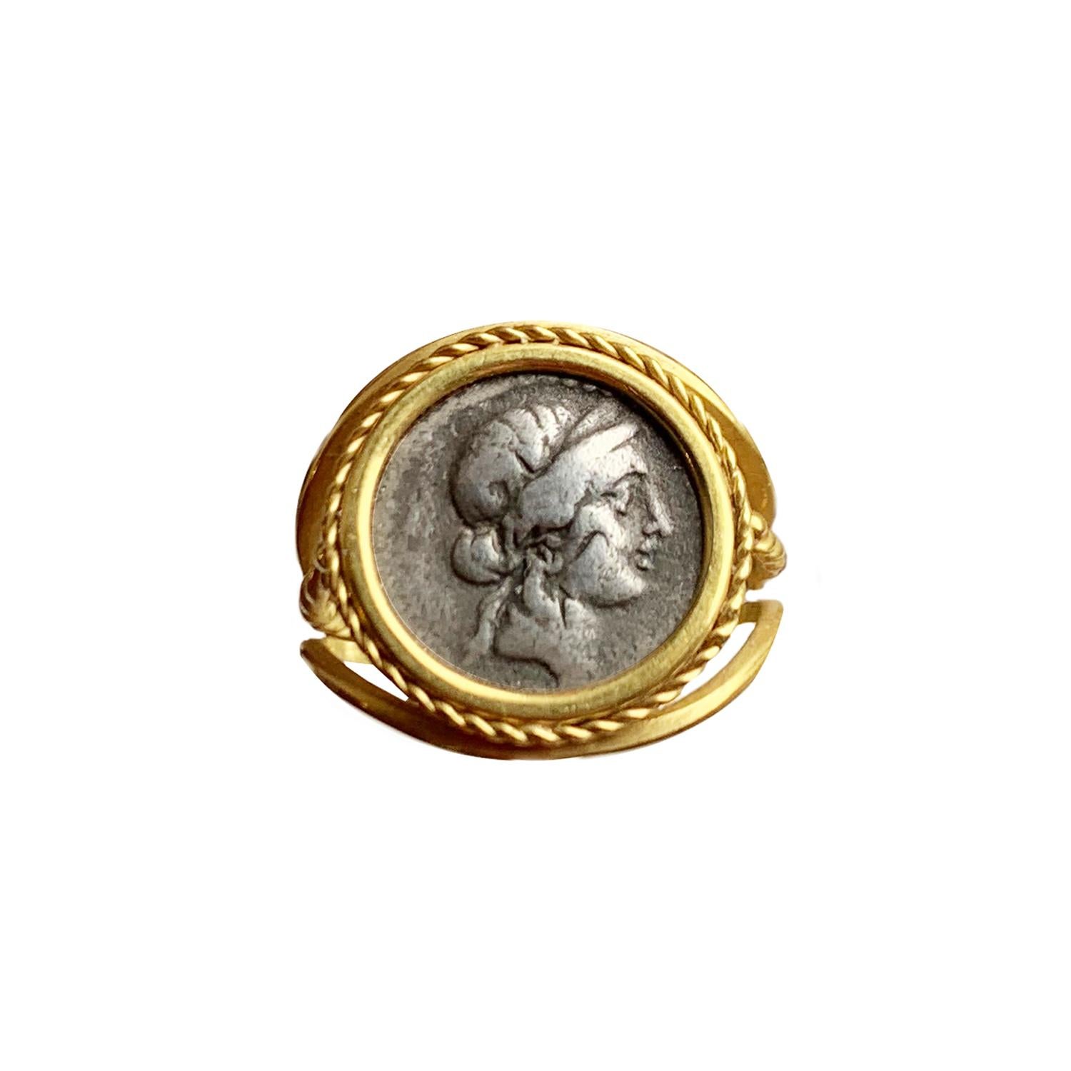 In this 18 Kt gold ring there is an authentic roman coin (silver denarius-1st century B.C. ) depicting the diademed head of Venus.
In reverse side of the coin there is Aeneas walking, carrying Anchise ( his father ) and Palladium.
Venus  is a Roman