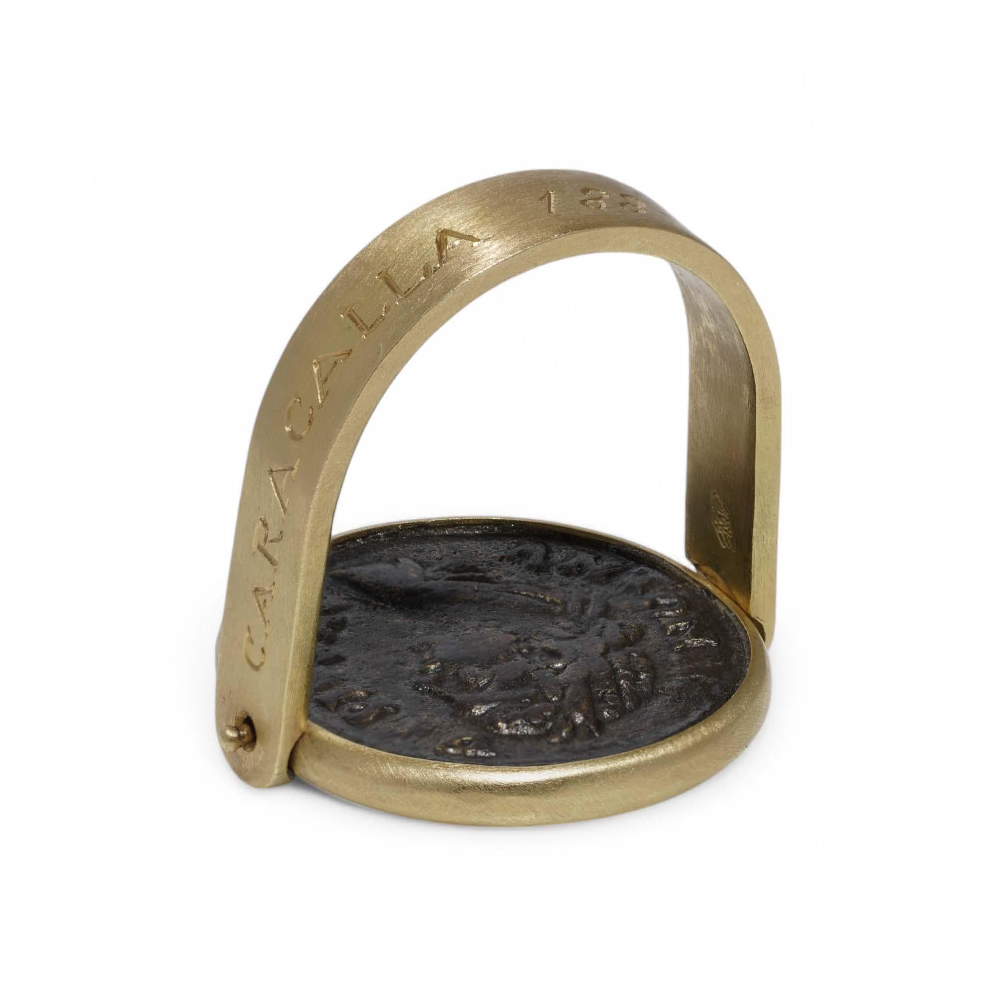 Cette bague remarquable et d'importance historique présente une authentique pièce de monnaie romaine, montée dans une monture artisanale en or jaune 18 carats. Ce design unique permet à la pièce de tourner à l'intérieur de sa lunette, offrant ainsi