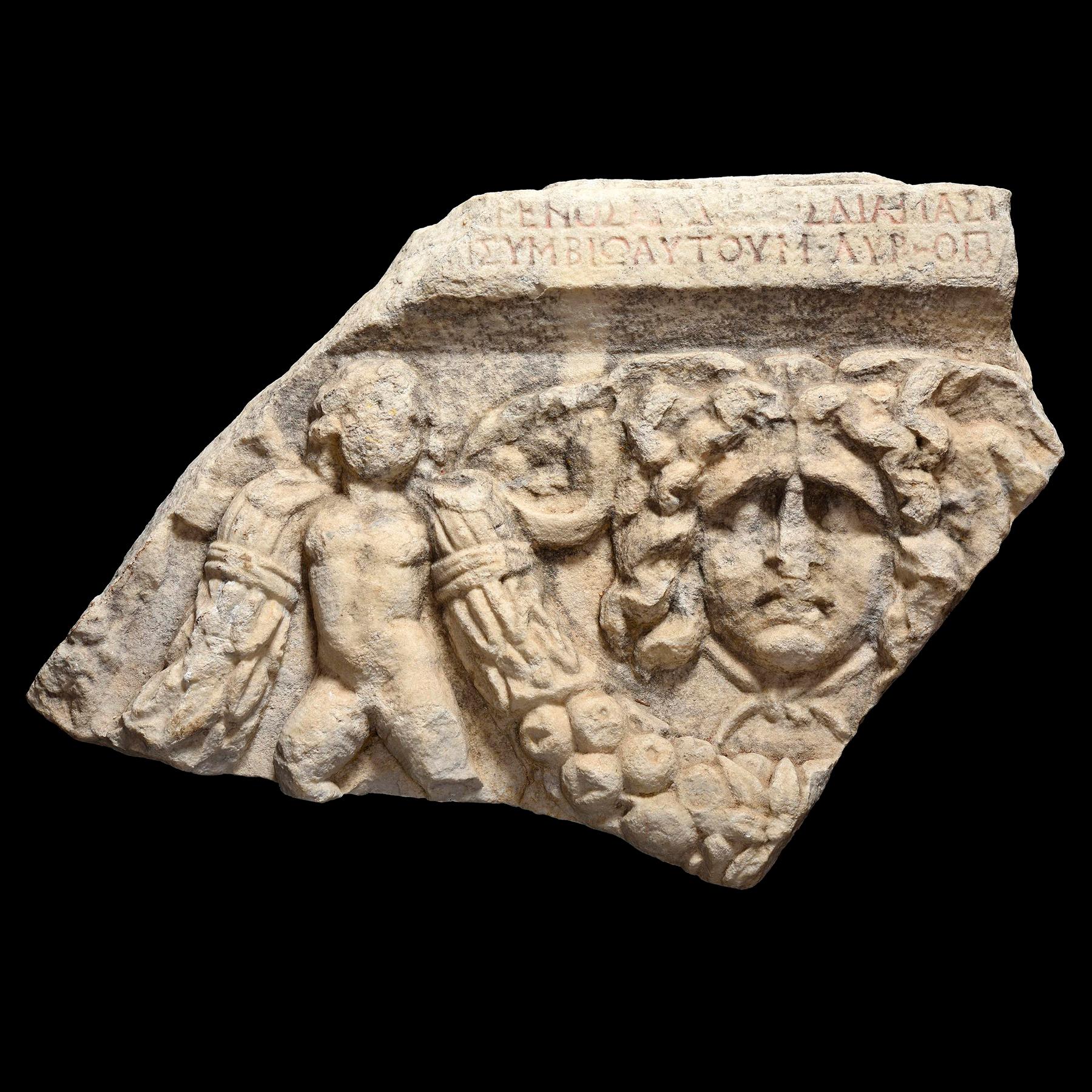 ITEM: Fragment of sarcophagus depicting a Gorgon and Eros with libertus Marcus Aurelius epitaph, Pamphylia Type
MATERIAL: Marble
CULTURE: Roman, Asia Minor
PERIOD: 2nd Century A.D, Antonine Period
DIMENSIONS: 55 cm x 82 cm x 13 cm, 100