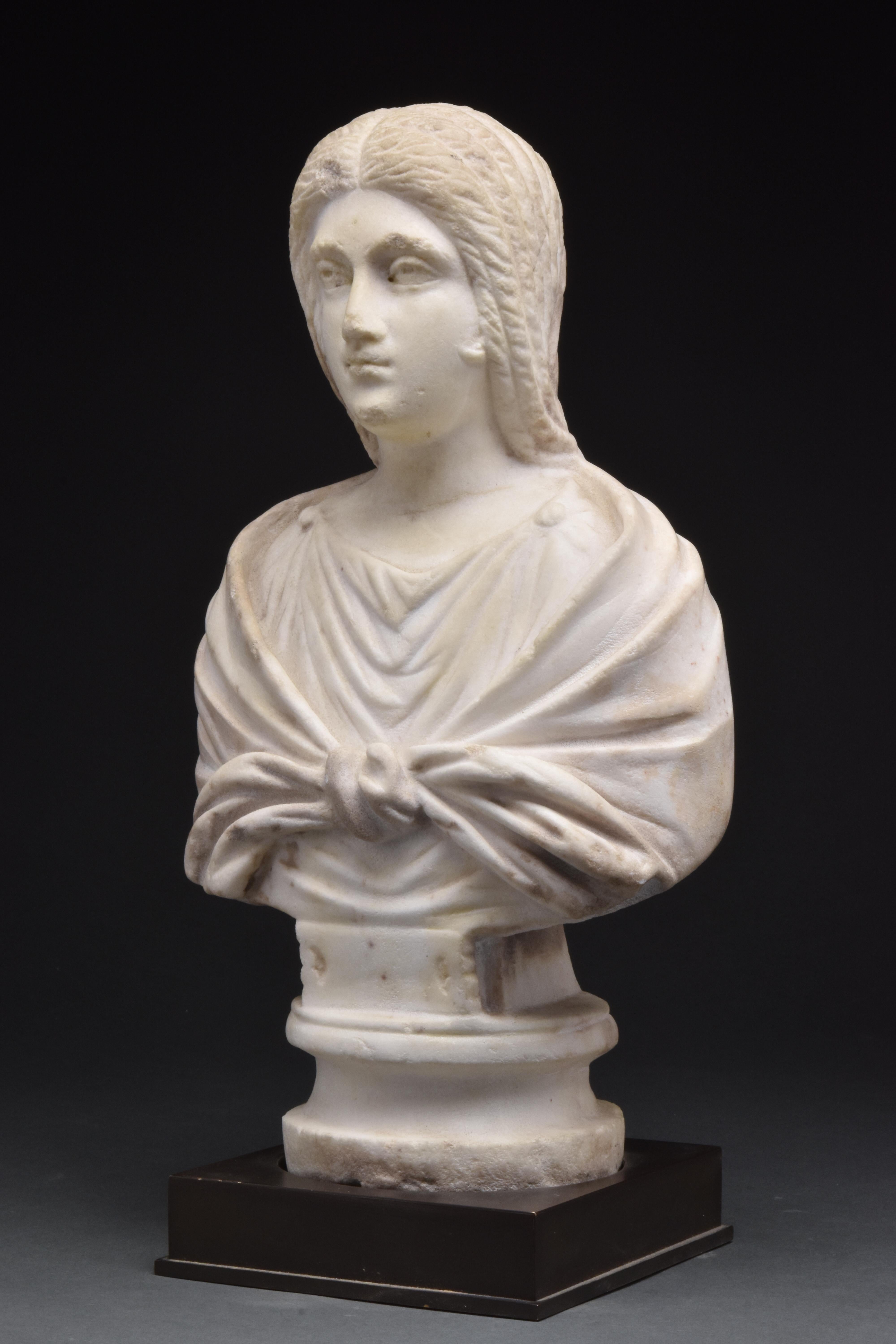 Late 2nd Century AD
A beautifully carved Roman bust of a woman with her hair elegantly parted at the centre as was fashionable during the late Antonine and Severan periods. Her face depicts a serene expression, with large eyes drilled to have deep