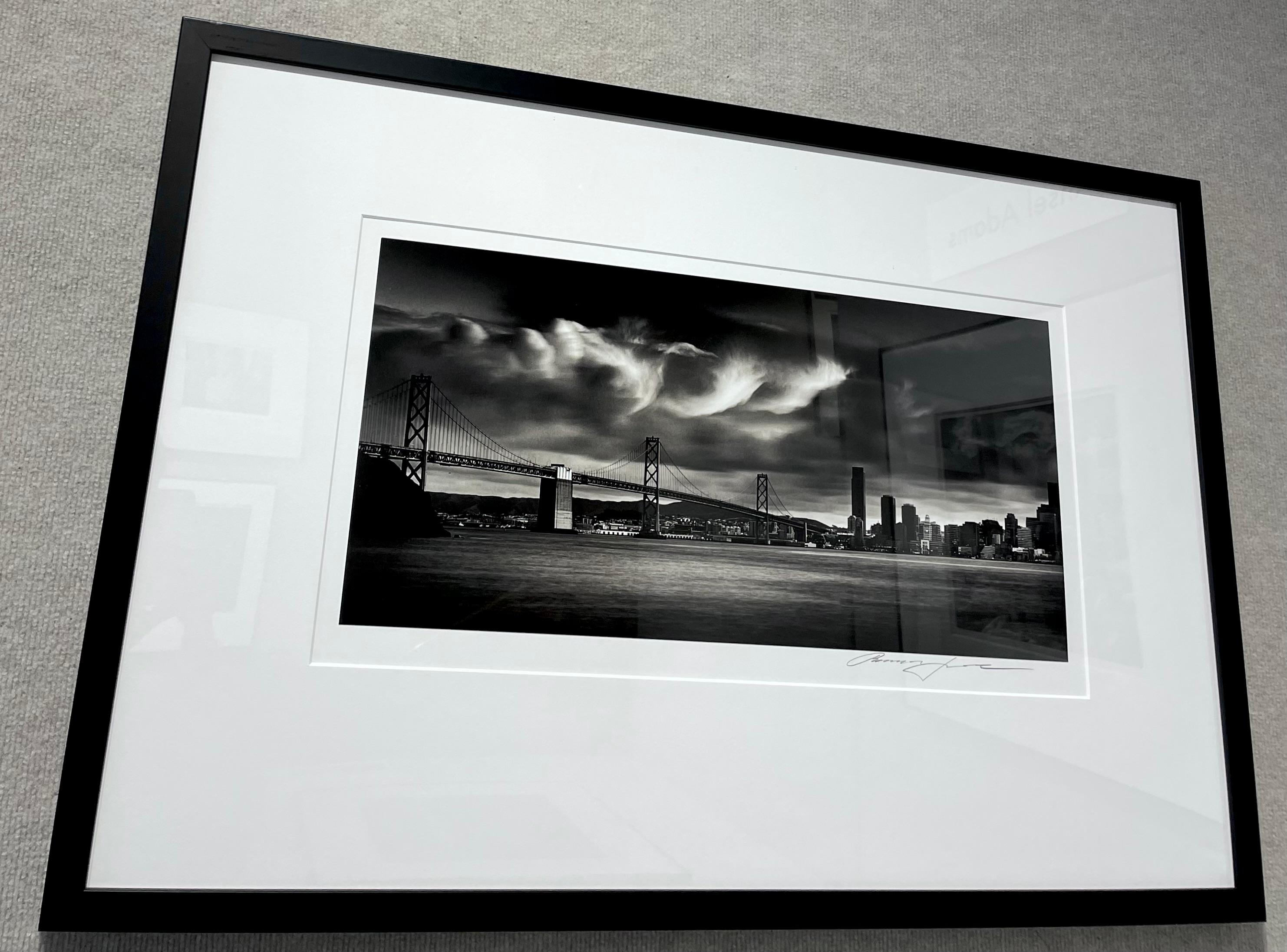 Nuages ondulants au-dessus du pont de la baie - Noir Landscape Photograph par Roman Loranc