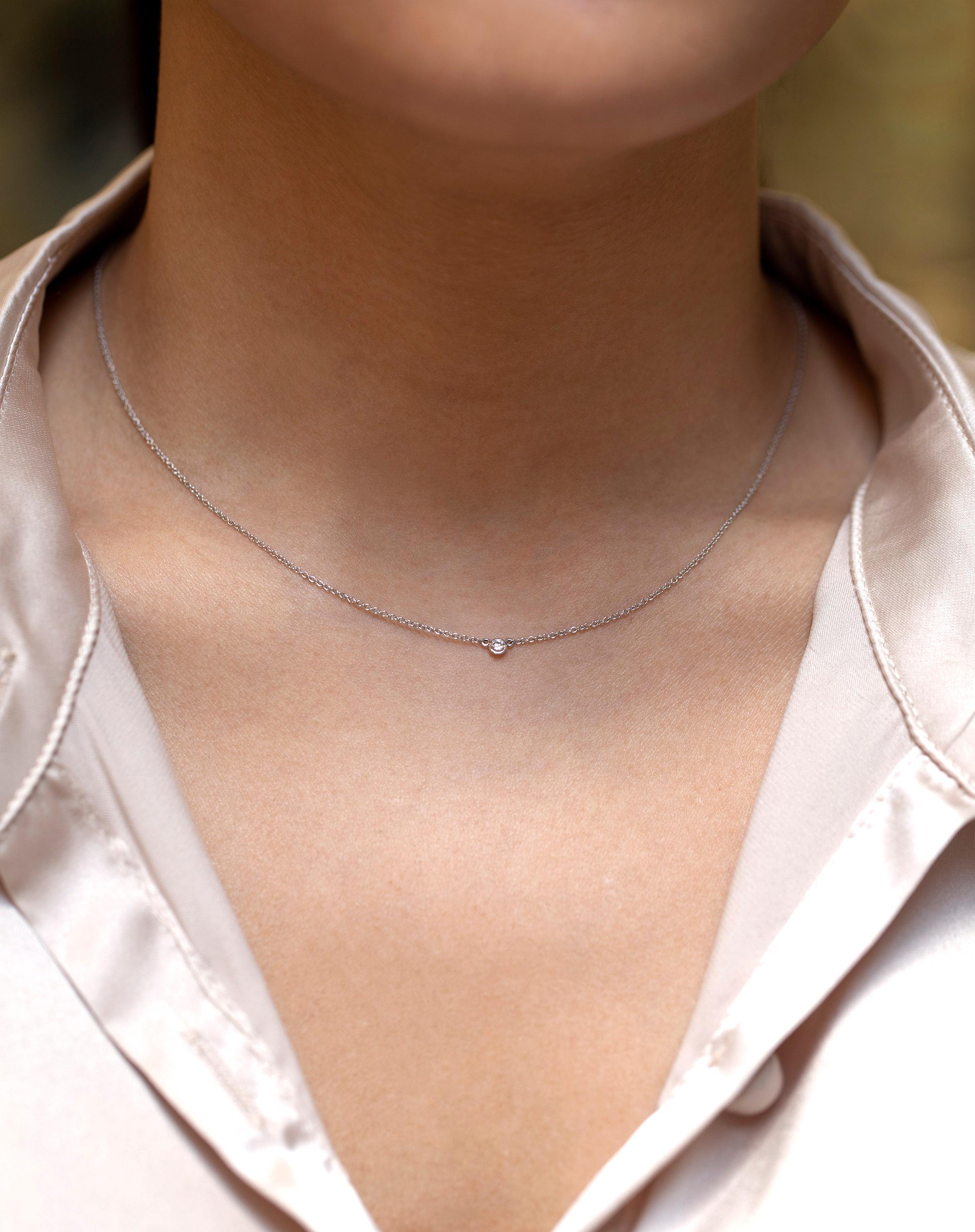 Un collier pendentif solitaire simple et polyvalent mettant en valeur un seul diamant rond de 0,06 carat dans une lunette en or blanc 14 carats. Attaché à une chaîne en or blanc de 16 pouces. 

Style disponible dans différentes gammes de prix. Les