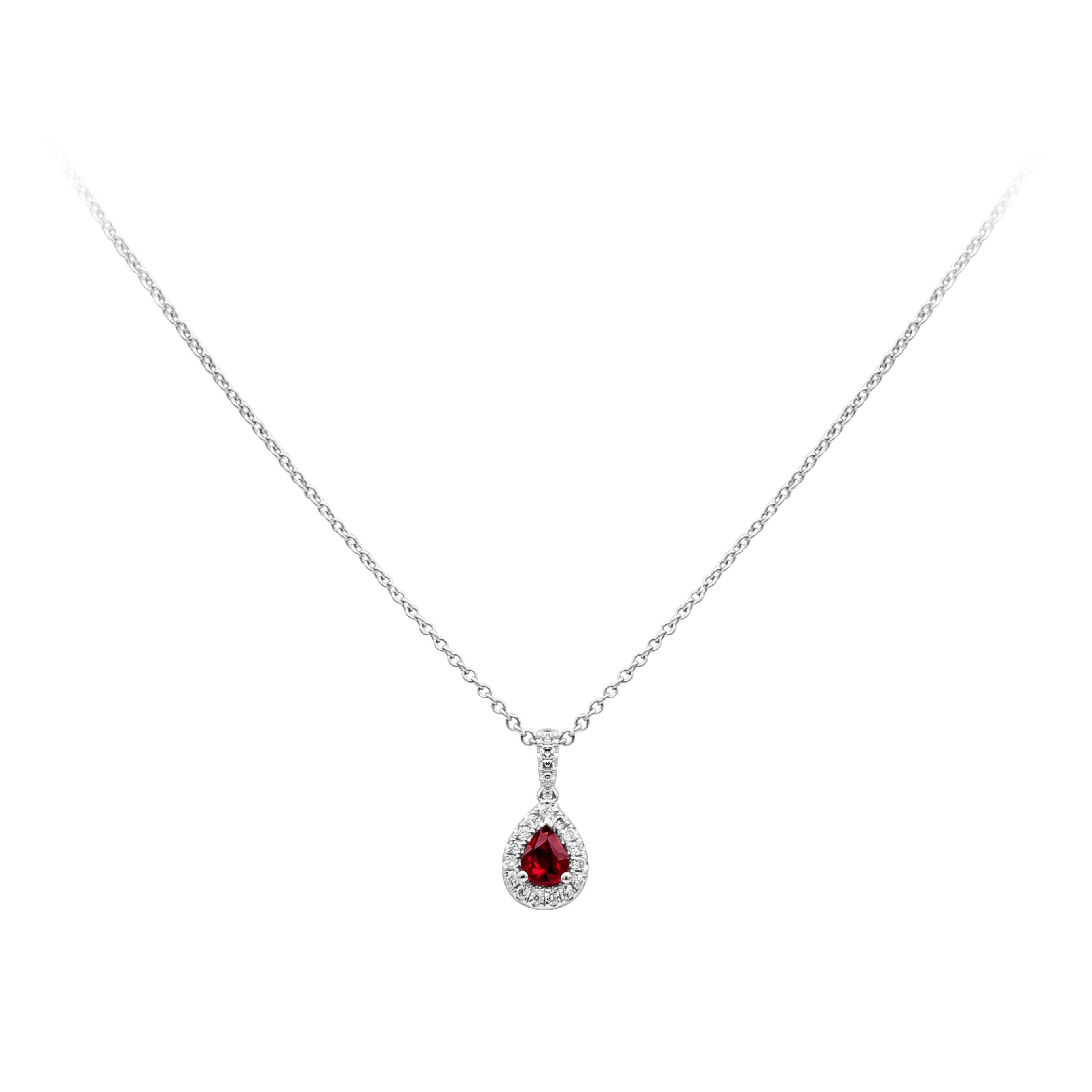 This simple and classic halo pendant necklace showcases a pear shape ruby weighing 0.35 carat, embellished by 20 pieces of round diamonds, weighing 0.11 carat total, F color and VS in clarity. Made in 14k and 18K White Gold. Suspended on 18 inches