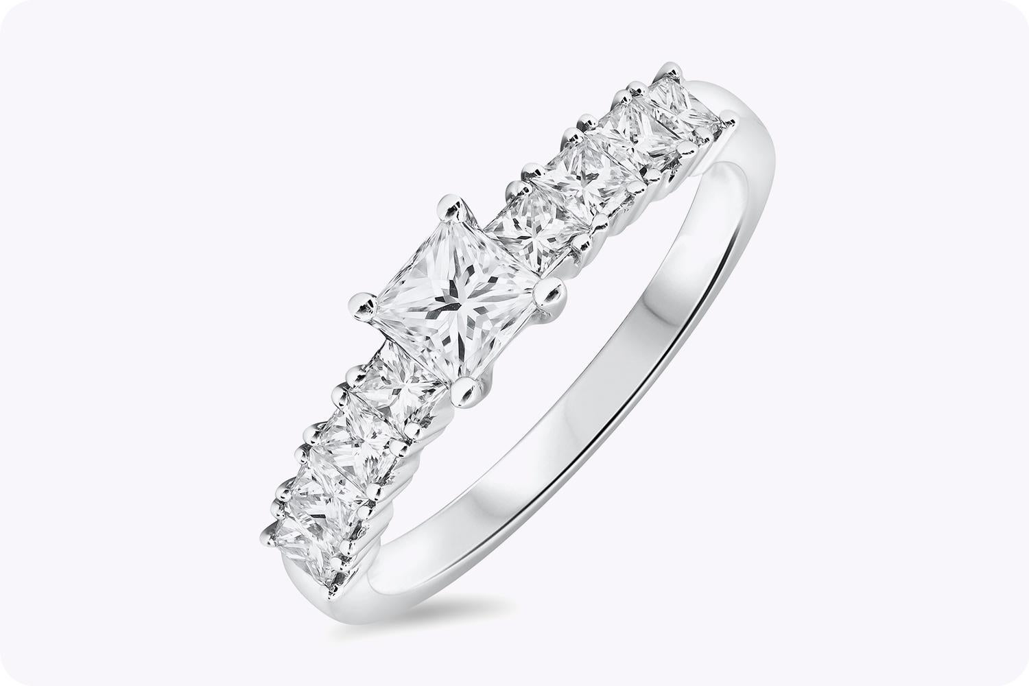 A unique and lustrous engagement ring showcasing a simple 0.39 carat princess cut diamond, accented by 4 smaller princess cut diamonds on either side. Accent princess cut diamonds weigh 0.67 carats total and are perfectly-matched. Set in polished 18