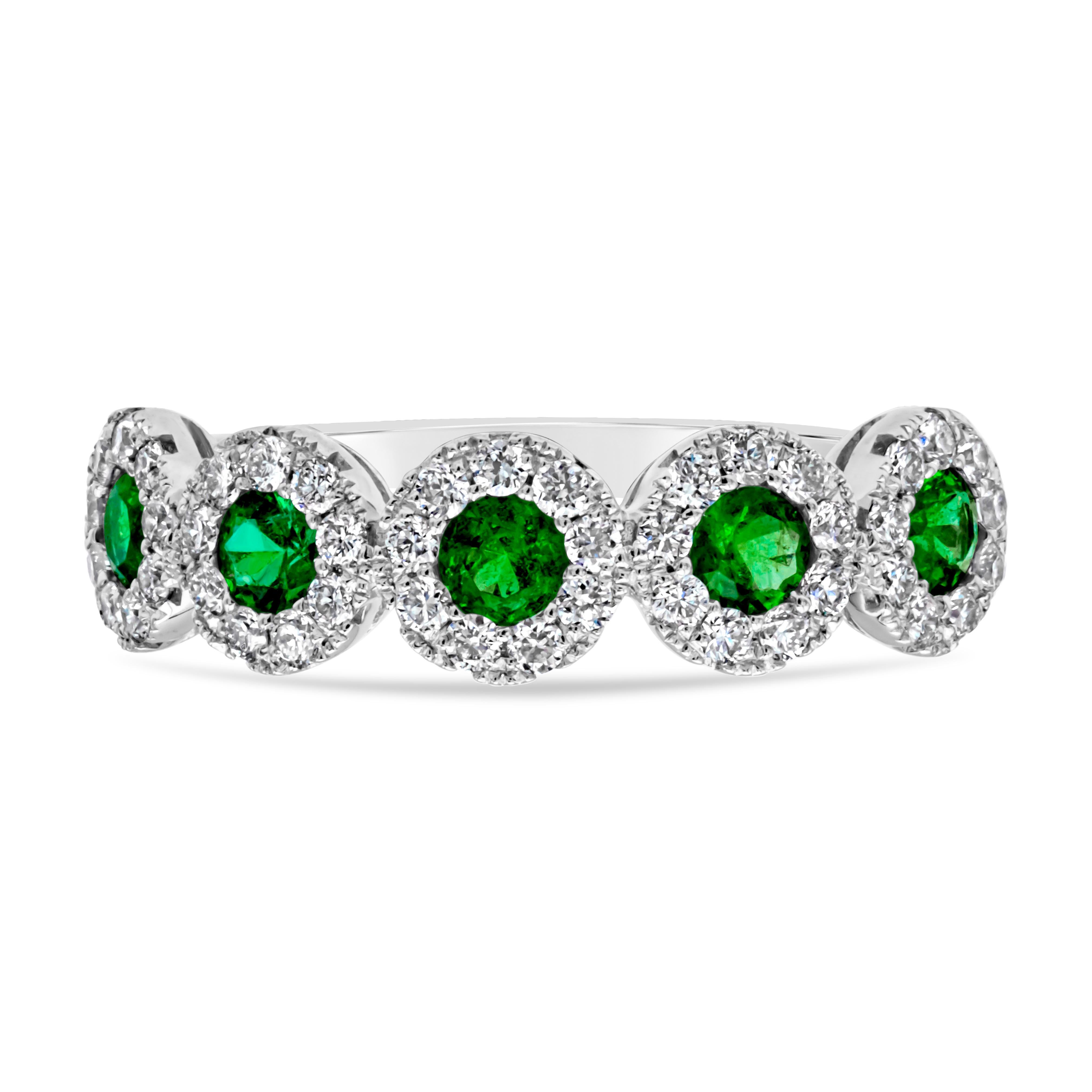 A classic and brilliant wedding band, featuring five color-rich round cut green emeralds weighing 0.40 carat total. Each emerald is surrounded by a halo of round brilliant cut diamonds weighing 0.39 carat total with F color and VS-SI clarity. Finely