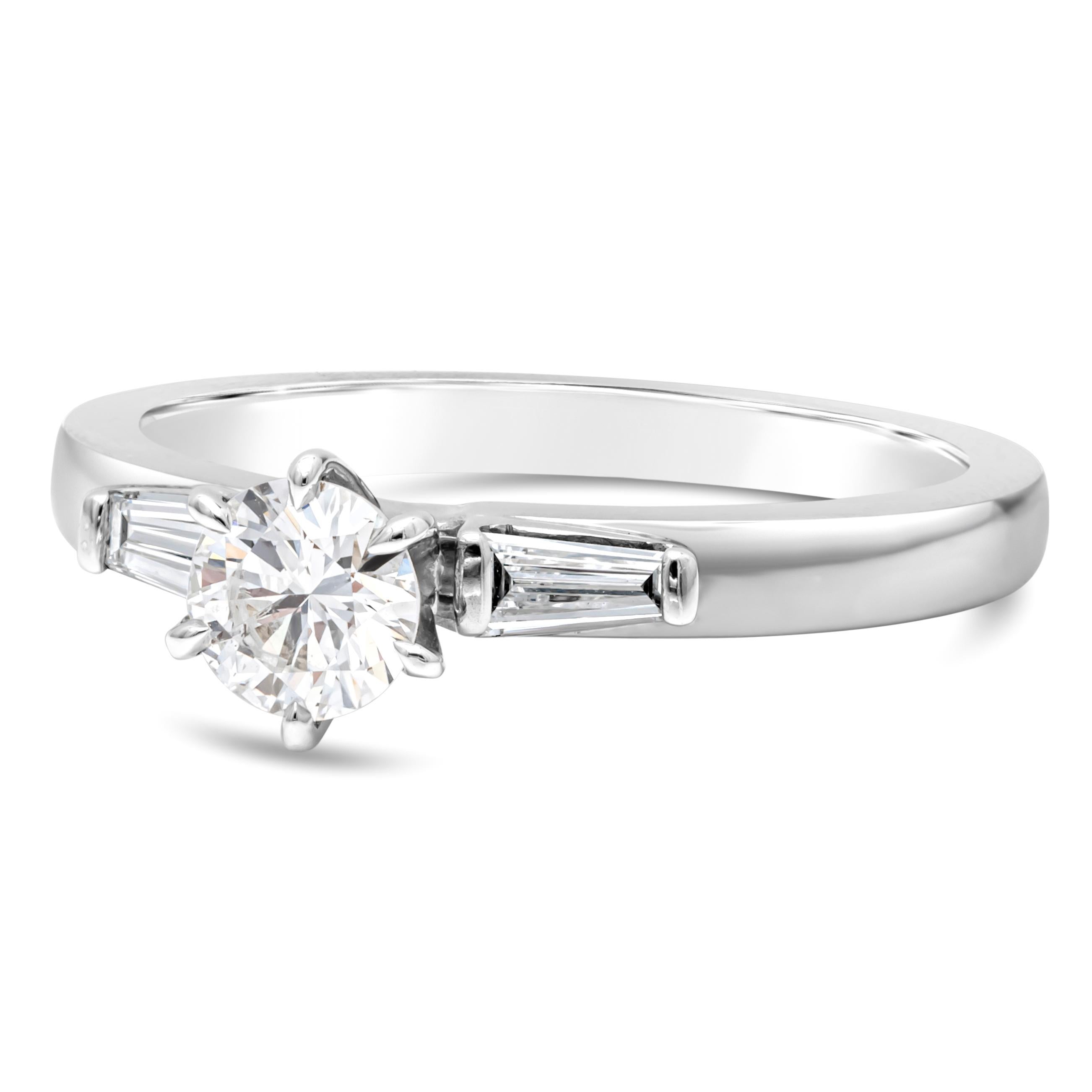 An elegant piece showcasing a vibrant 0.45 carat round brilliant diamond accented with tapered baguette 0.18 carat total diamonds on each side. Center stone is  D color, SI1 in clarity. Set in a six prong basket setting. Finely made in 18K White