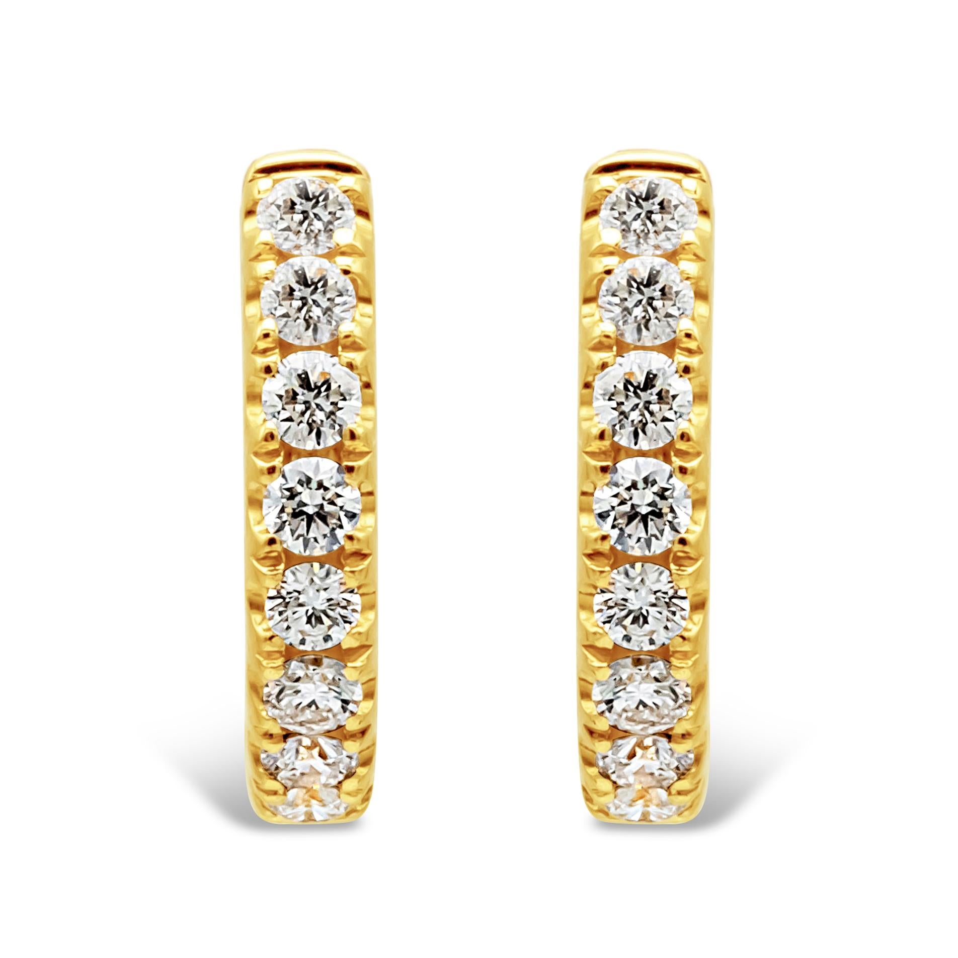 A simple and classic pair of huggie hoop earrings showcasing a row of 16 round brilliant diamonds set in a half-way weighing 0.46 carats total, F-G color and VS-SI1 in clarity. Set in a four prong basket setting and Finely made in 18k yellow