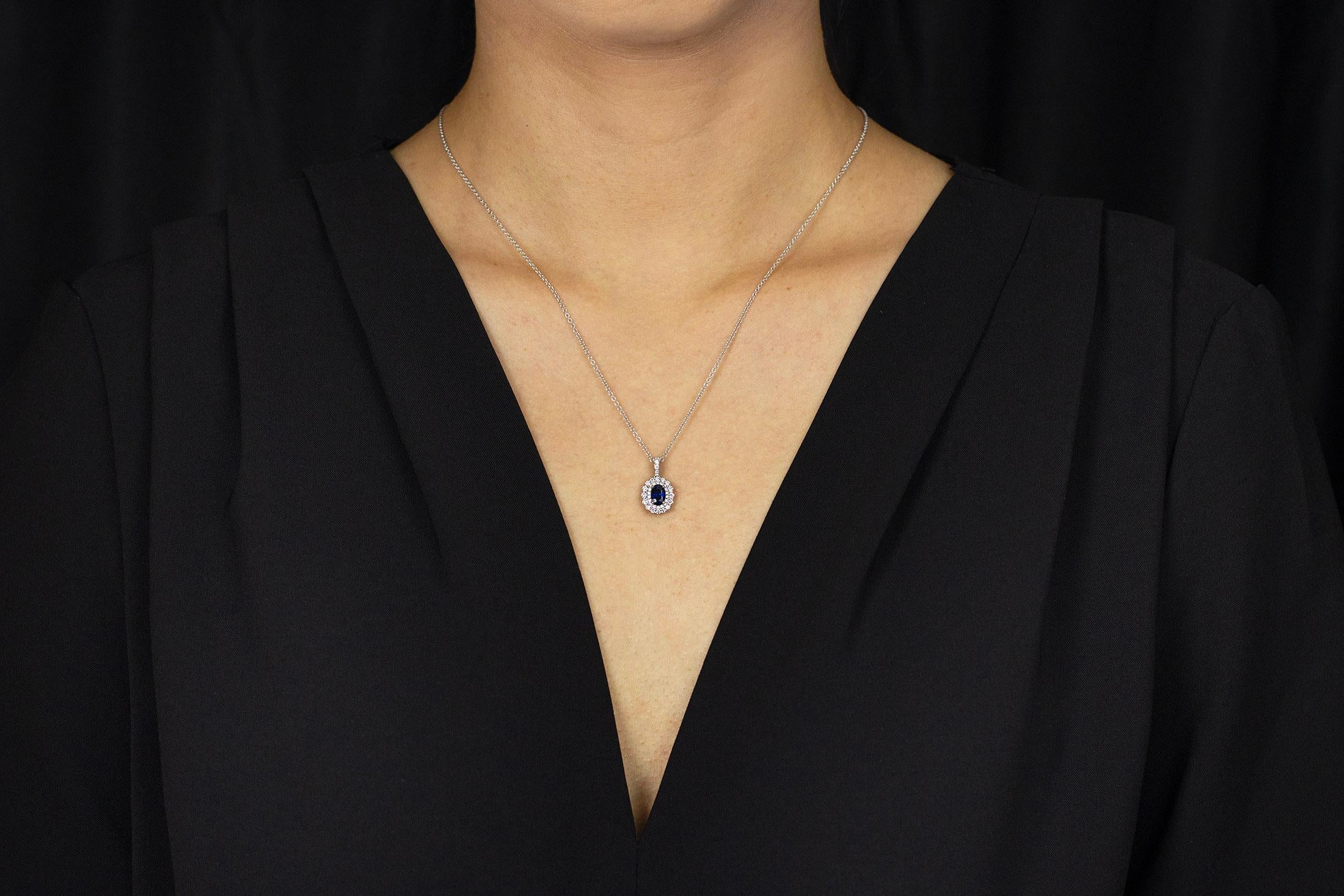 A simple pendant necklace showcasing a 0.52 carat blue sapphire, complemented by a round brilliant diamond surround. Diamonds weigh 0.37 carats total. Attached to a 18 inch white gold chain, Made in 18k White Gold. 

Style available in different
