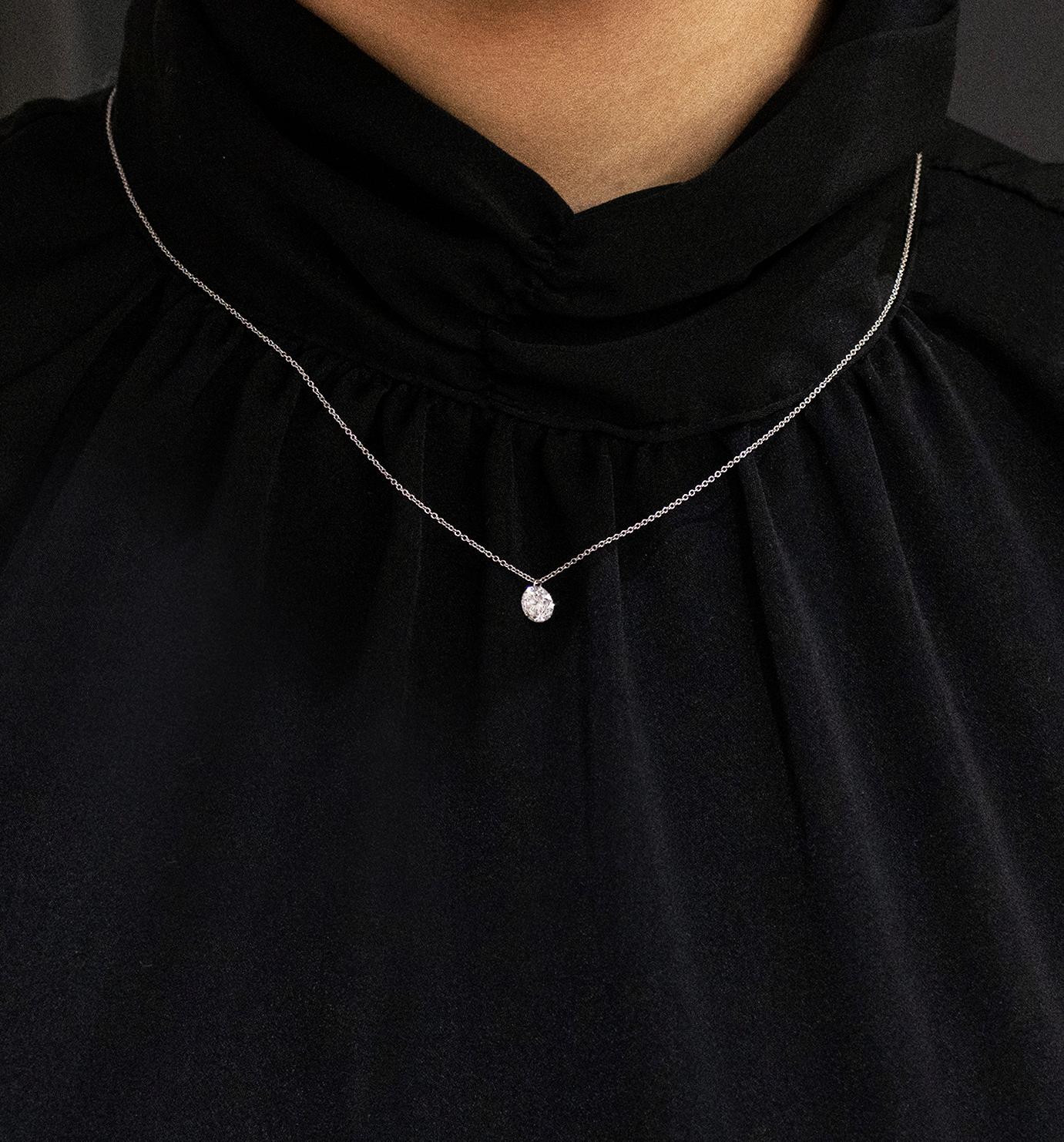 A unique solitaire pendant necklace showcasing a 0.74 carat round brilliant diamond, finely drilled to attach to a white gold bale made in 14 karat white gold. Attached to an 16 inch white gold chain (adjustable upon request).