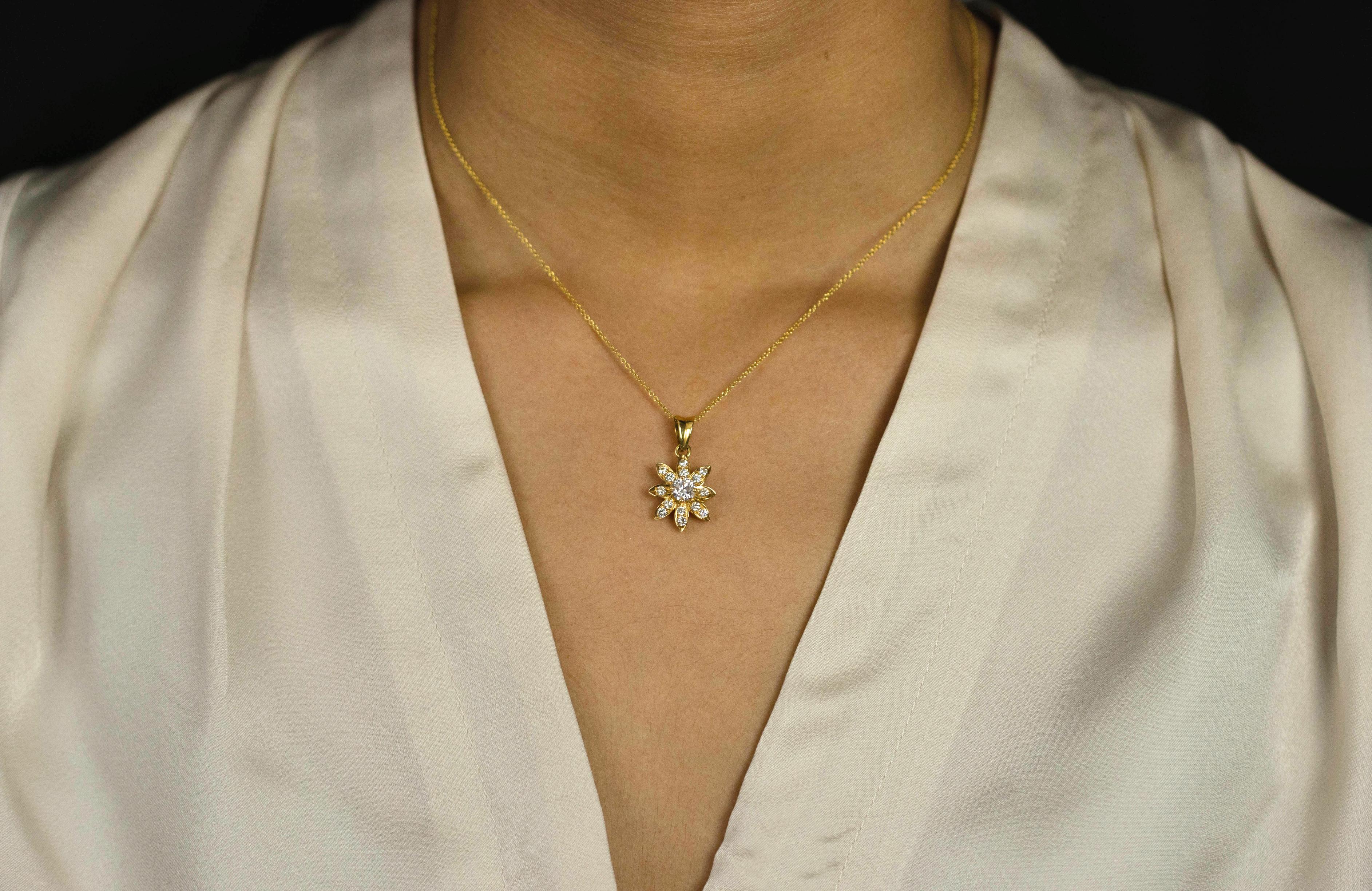 A brilliant piece of jewelry showcasing a brilliant round diamond center, accented by smaller round diamonds in a chic starburst design. Diamonds weigh 0.84 carats total. Made in 14k yellow gold. Suspended on a 16 inches adjustable  yellow gold