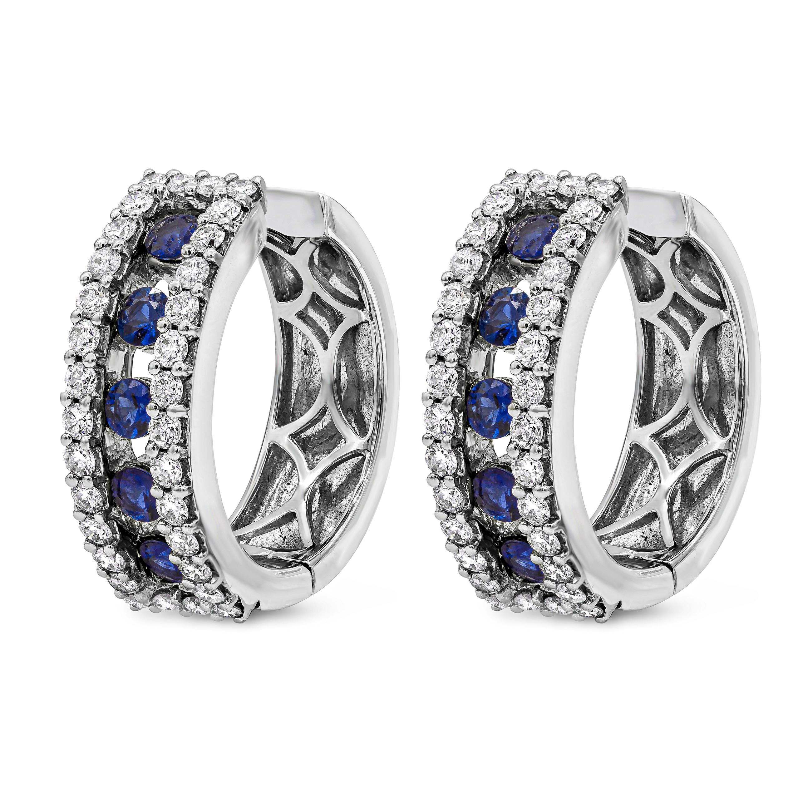 A stylish and versatile style hoop earrings showcasing round cut blue sapphires weighing 1.09 carats total. Channel set in a diamond encrusted 18k white gold mounting, set in a timeless shared prong basket setting. Diamonds weigh 0.93 carats